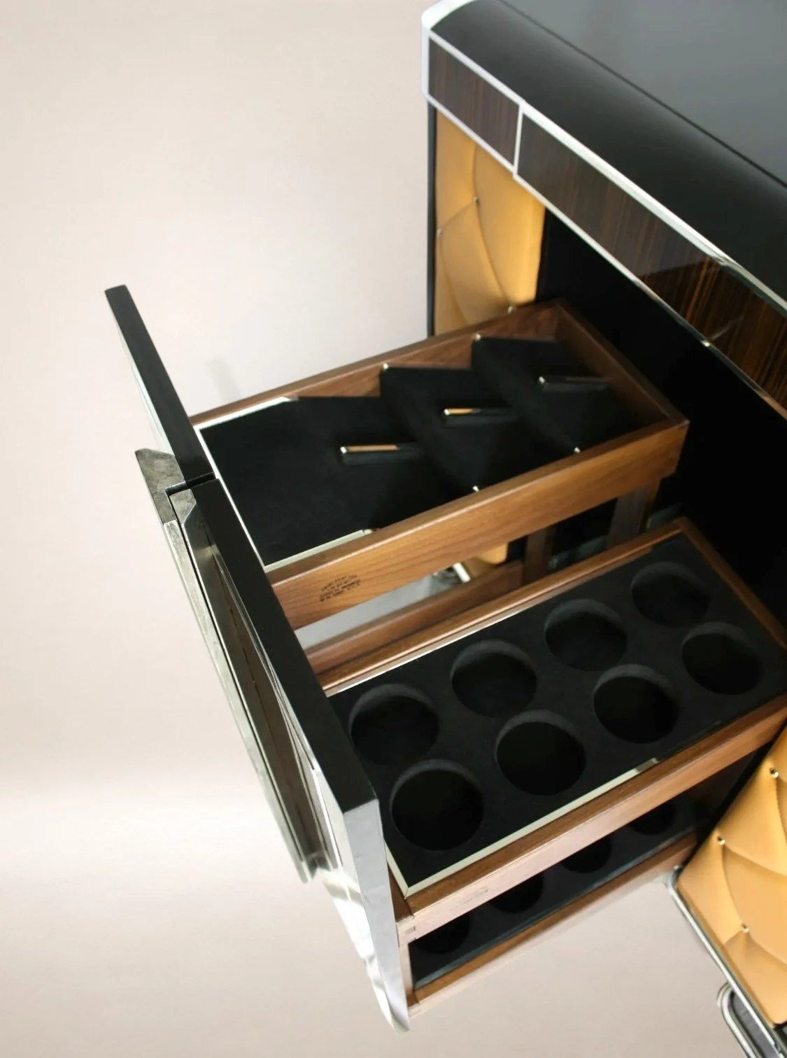 An open liquor cabinet with bottles stored inside, next to a yellow chair.