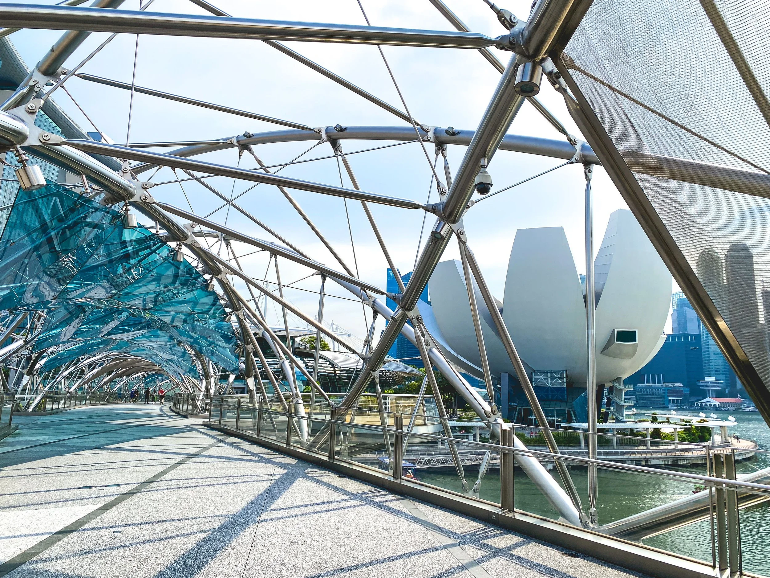 Modern architectural structure with interconnected metallic and glass elements, set in an urban environment, with walkways and buildings visible in the background.
