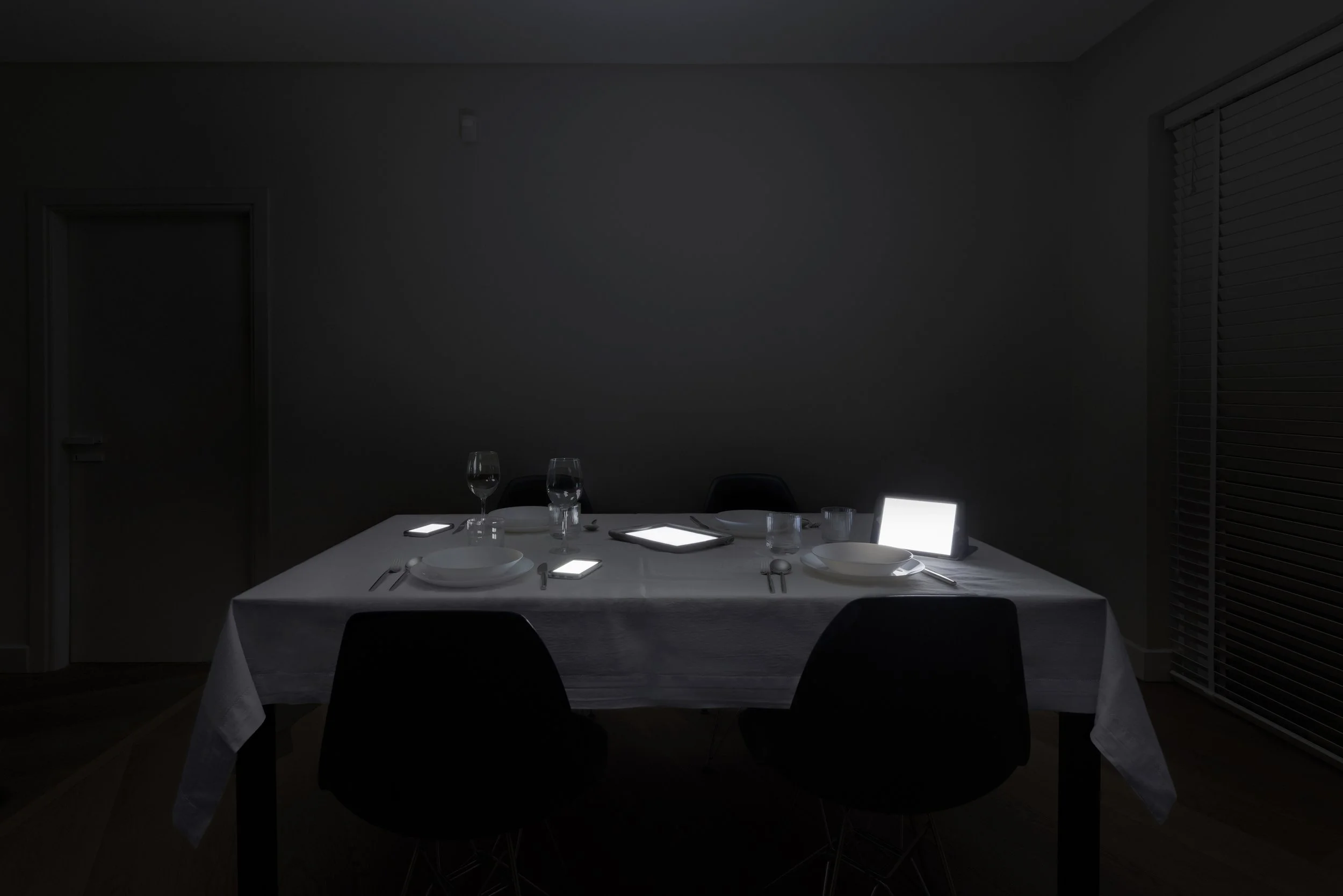 Anniversary Dinner from Family Portraits by Maria Mavropoulou, a staged photograph of digital devices occupying an intimate dining scene and questioning technology’s place in human relationships.