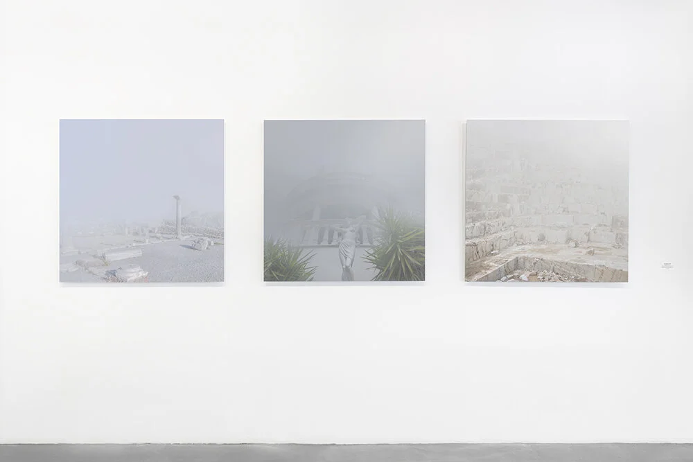 Installation view of three uncanny, fog-covered Mediterranean landscapes from Inner State, including ancient ruins, a classical statue and a marble quarry.