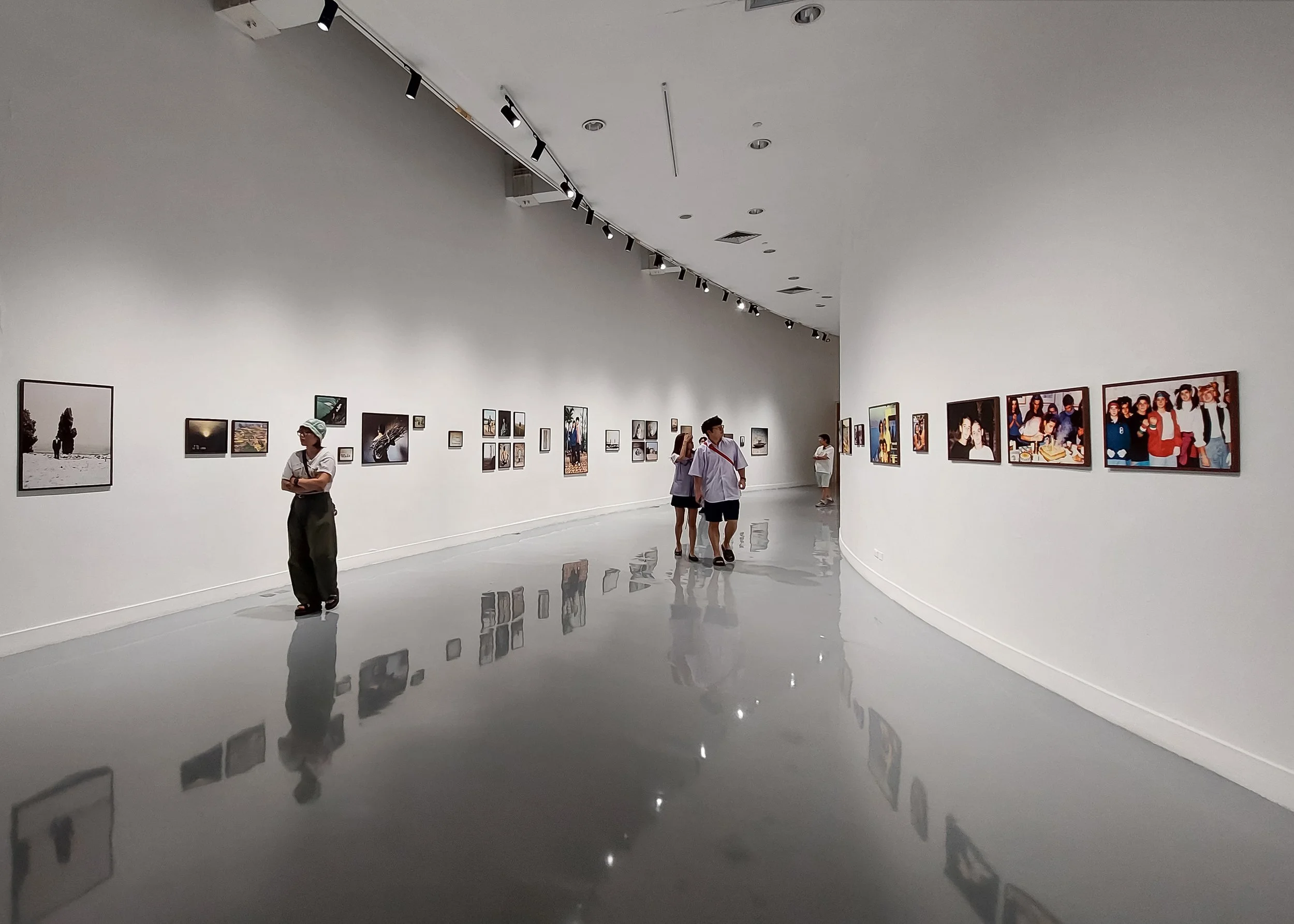 Installation view of Imagined Images in Photography Never Lies at BACC Bangkok in 2024, showing AI-generated family photographs in the gallery.