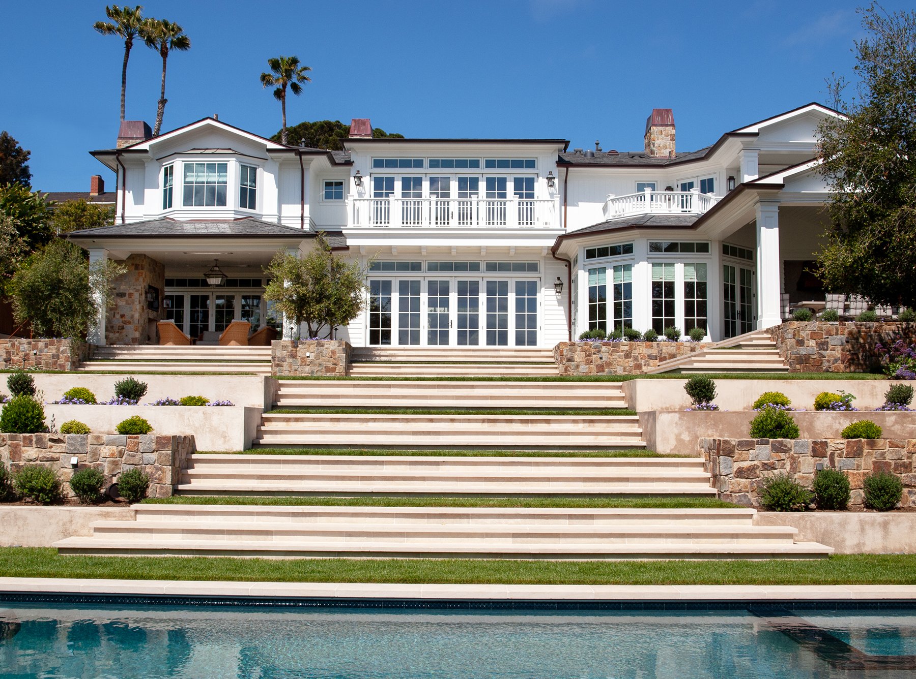 Terraced grounds step down to pool level.