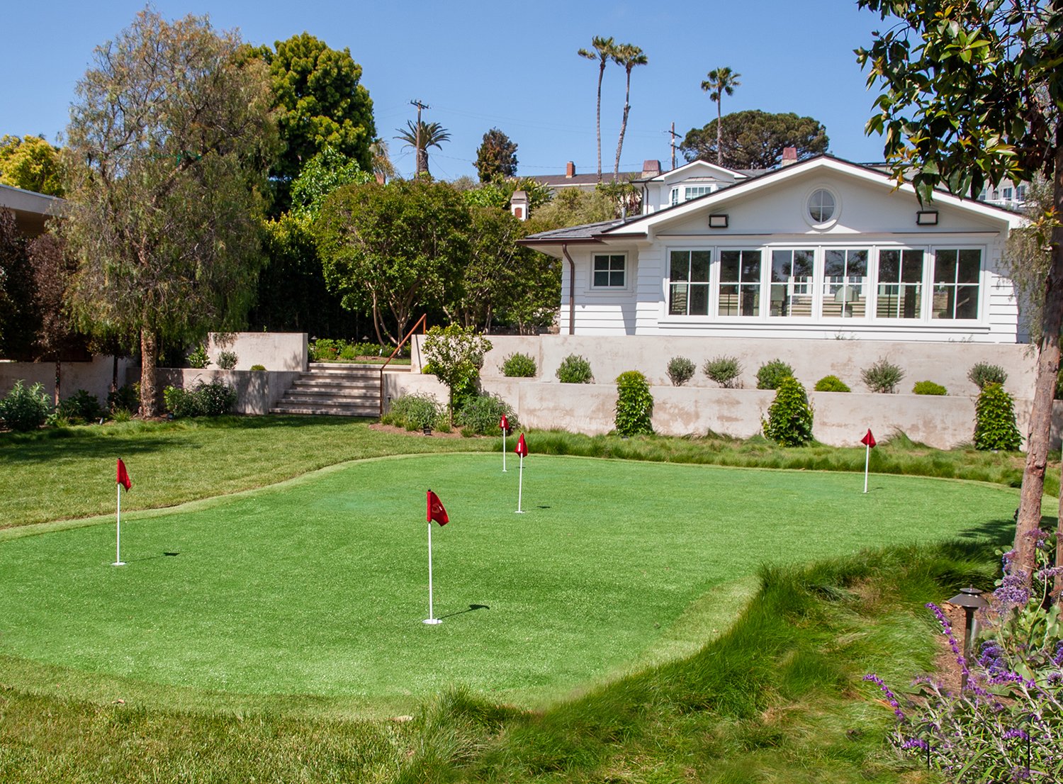 Putting green in lush private garden with mature trees, soft grasses and shrubs.