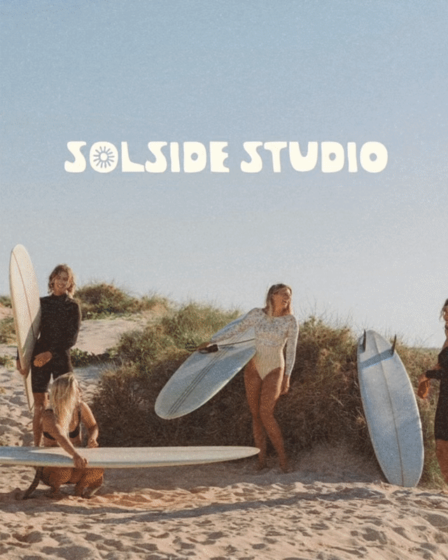 Children with surfboards on a sandy beach with dunes and shrubbery, under a clear blue sky, with the words 'SOLSIDE STUDIO' in white font at the top.