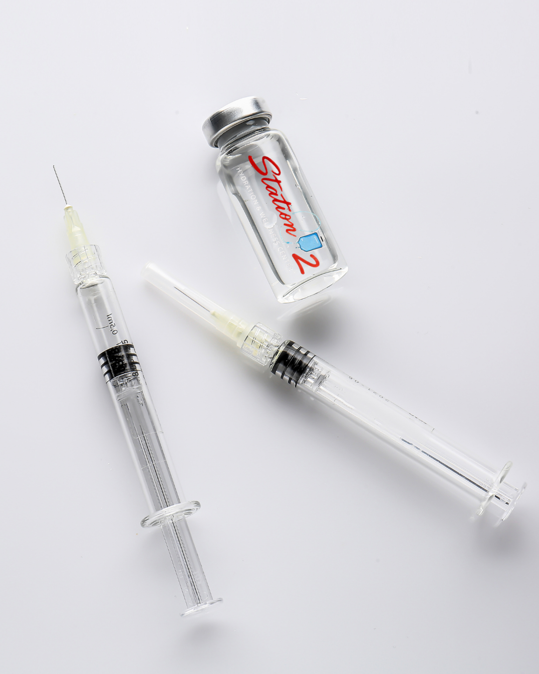 A bottle of saline solution and two syringes on a white background.