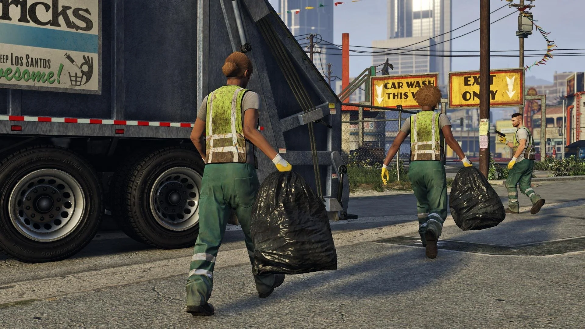 Four trash collectors wearing reflective vests and gloves are emptying trash bags into a garbage truck on a city street. There are signs for car wash and exit nearby, with tall buildings in the background.