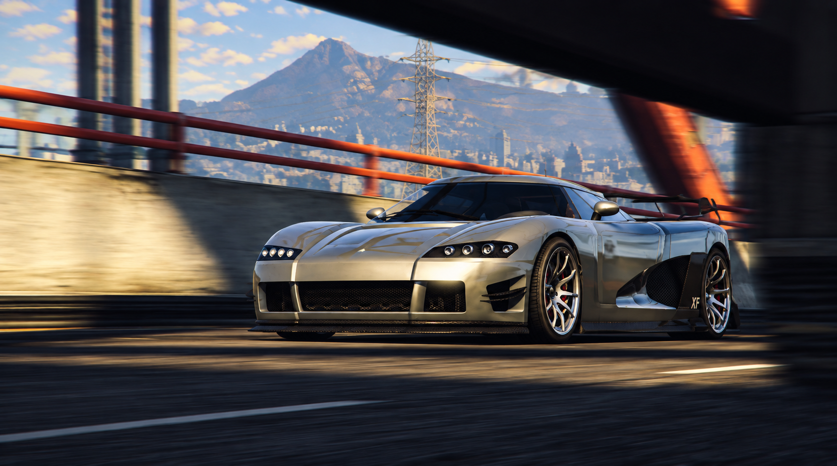 A silver sports car racing on a city highway with a mountain, city skyline, and power lines in the background.