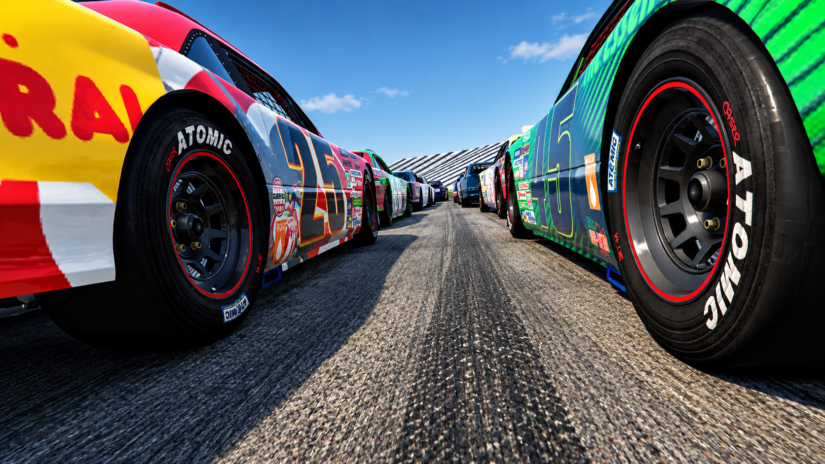 Close-up of race cars with colorful paint and tires on racing track under blue sky.
