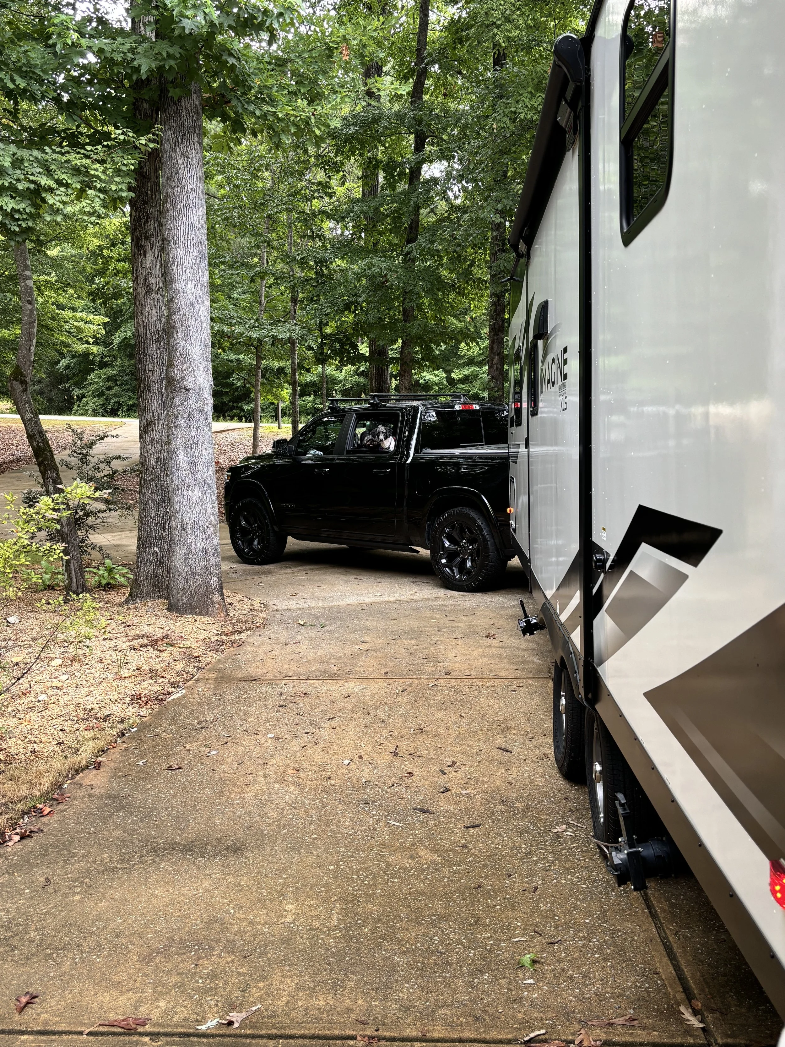 A truck pulling a camper with dogs in the back seat