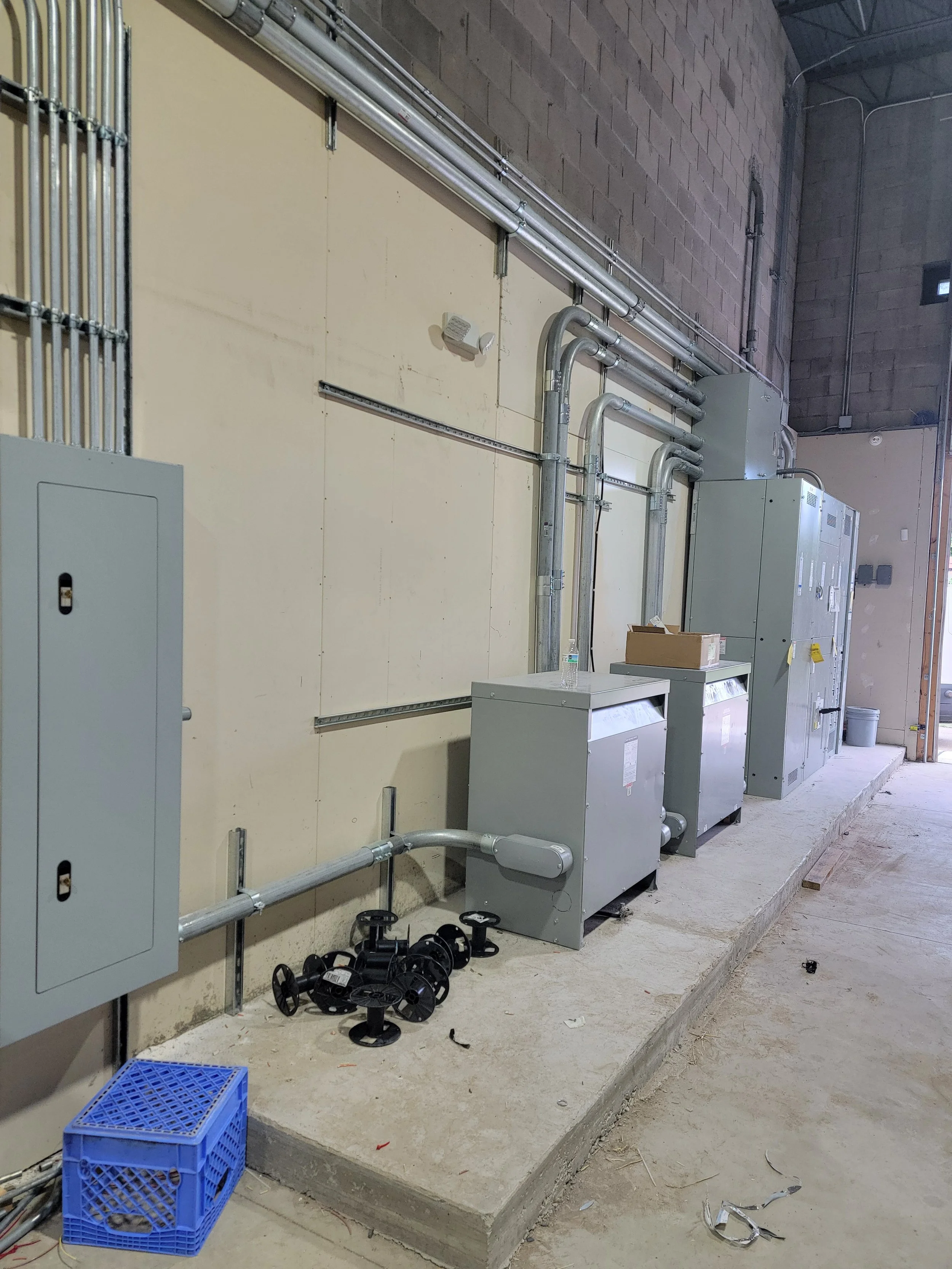 Industrial equipment with electrical panels, PVC piping, and tools in a construction or maintenance area.