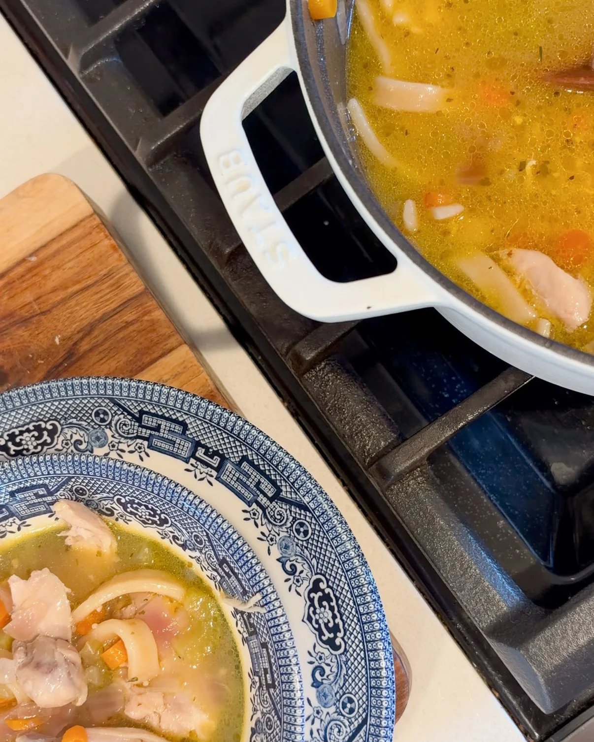 Homemade chicken noodle soup with shredded chicken, carrots, celery, and egg noodles served in a bowl with sourdough bread.