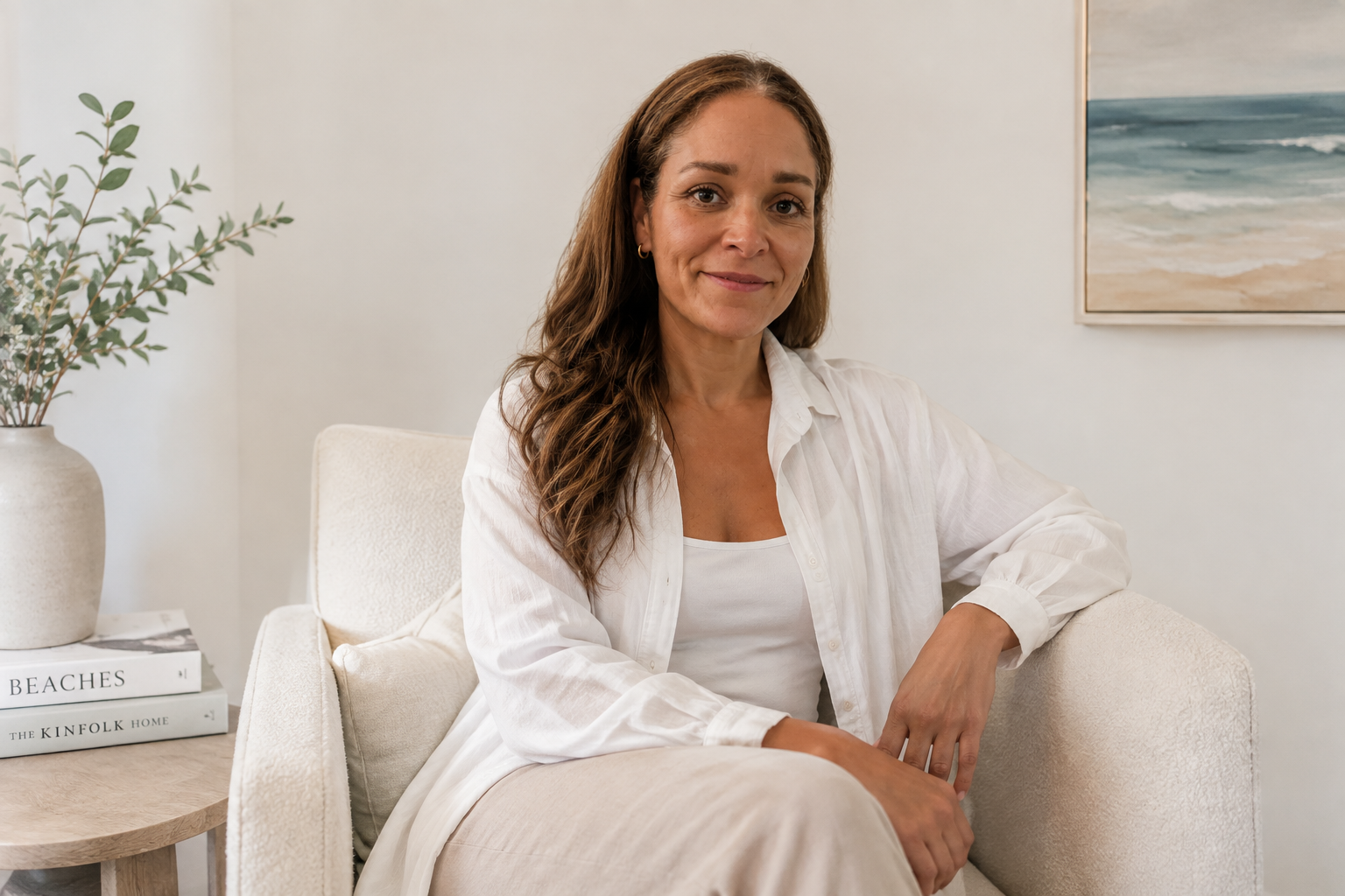 author sitting in chair, smiling at the camera, dressed in white button up shirt with brown hair
