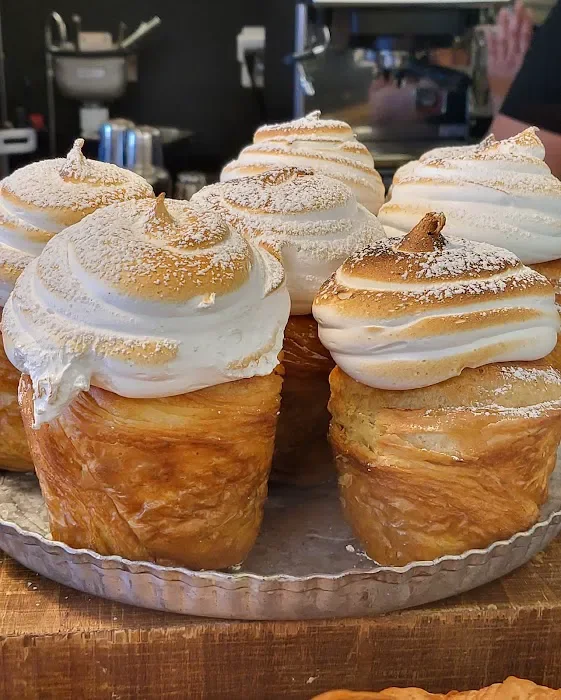 Pastry cups filled with meringue topped with toasted marshmallow on a tray.