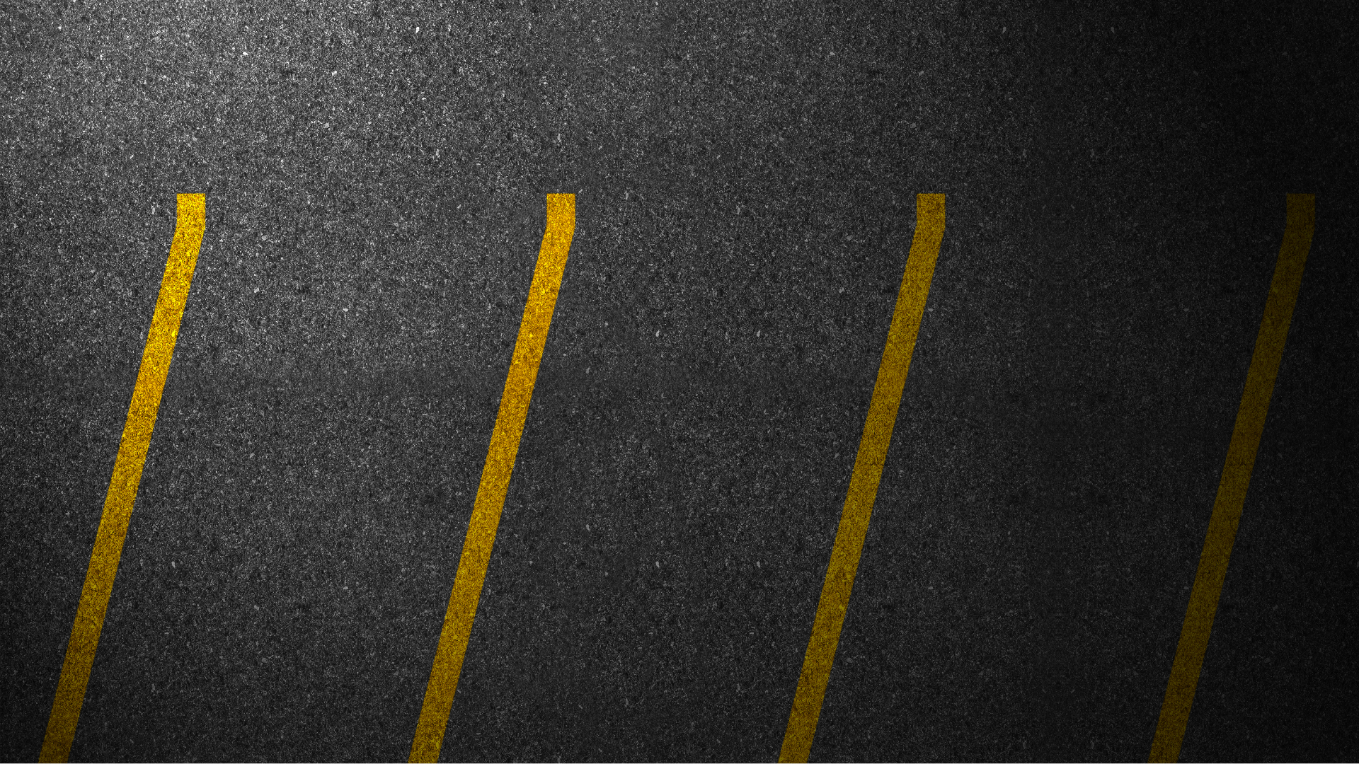A section of a paved road with yellow lane markings, viewed from above.
