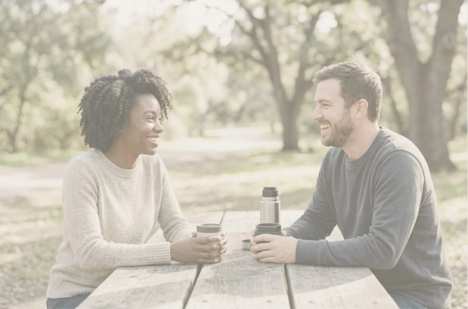man and woman sitting in park smiling
