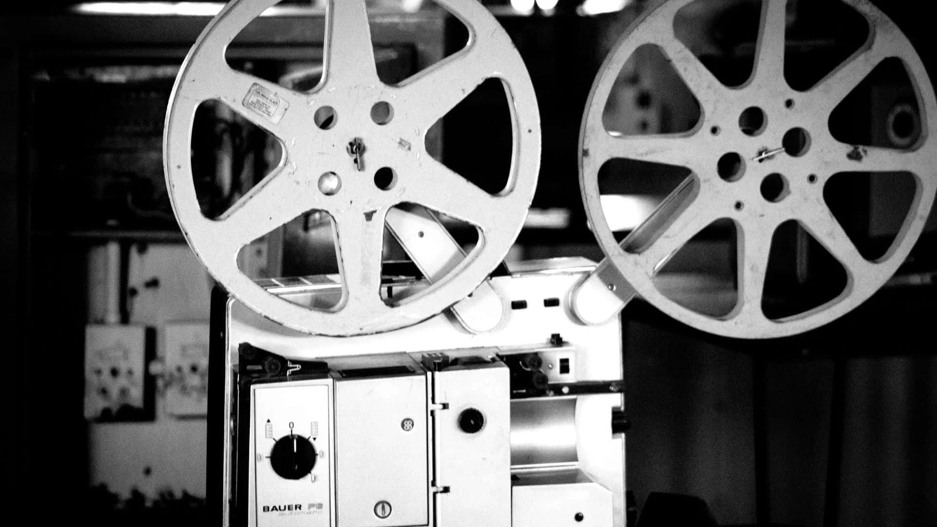 Two vintage film projectors with large reels, black and white photograph.