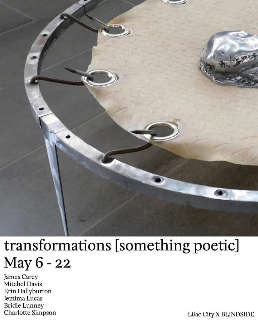 Close-up of a metallic circular art piece with hooks and a paper-like surface underneath, positioned on a tiled floor.