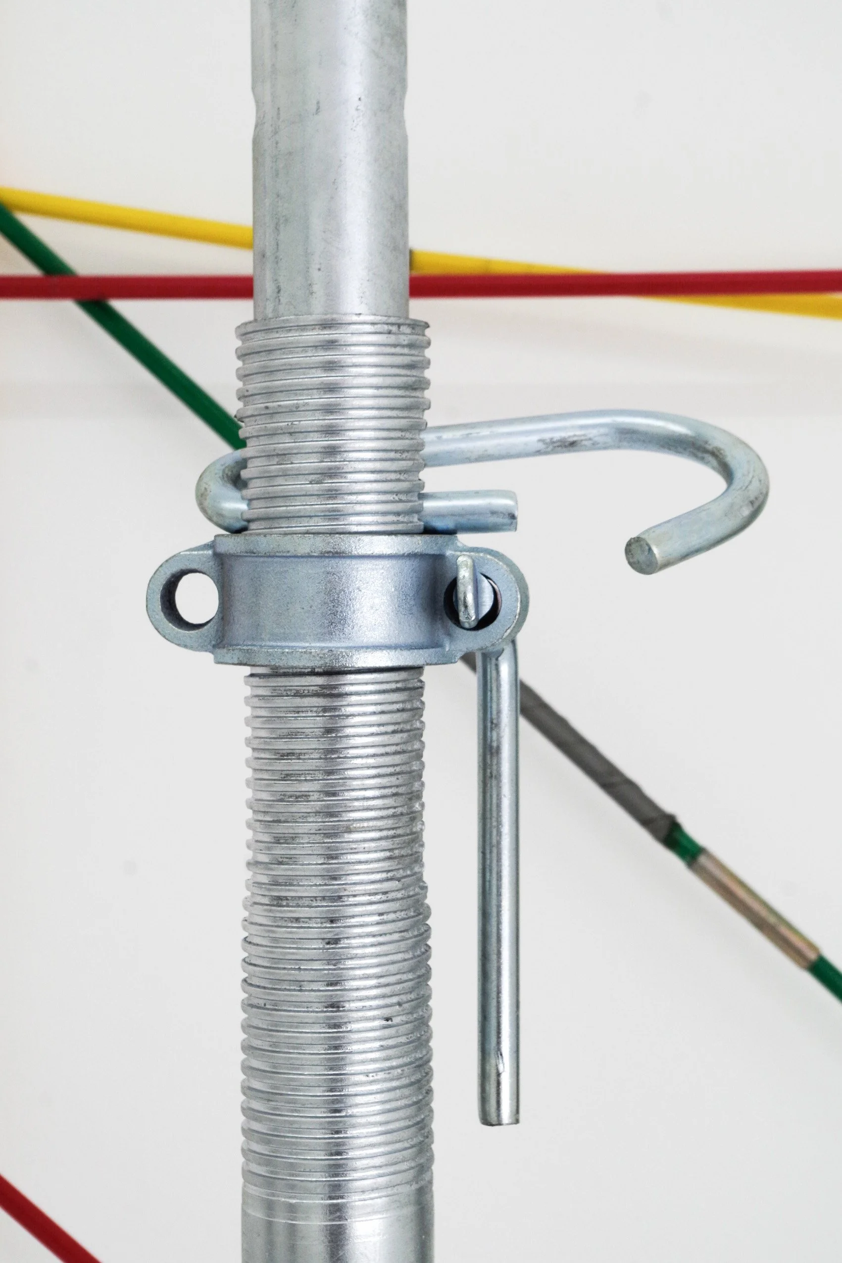 Close-up of a metal cable reel stand with yellow, red, and green cables in the background.