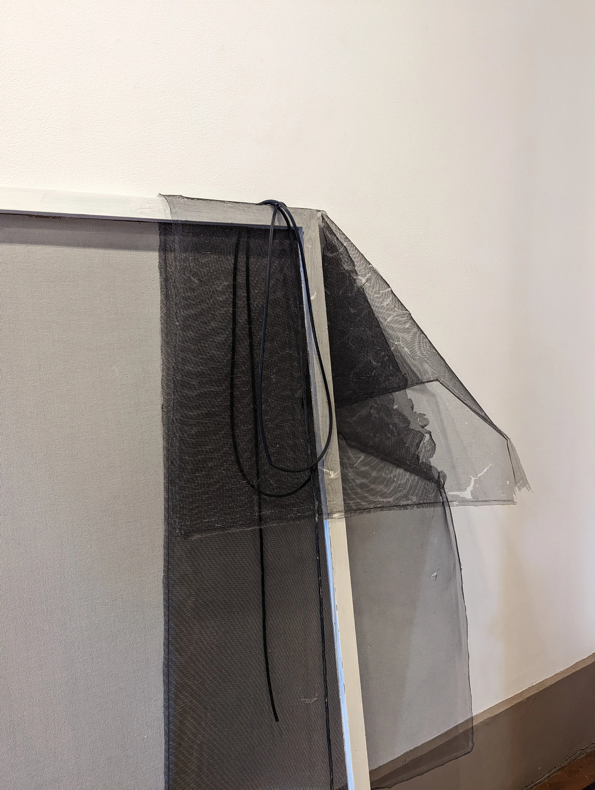 A black bug zapper with a cord hanging from its top, mounted on or near a wall.