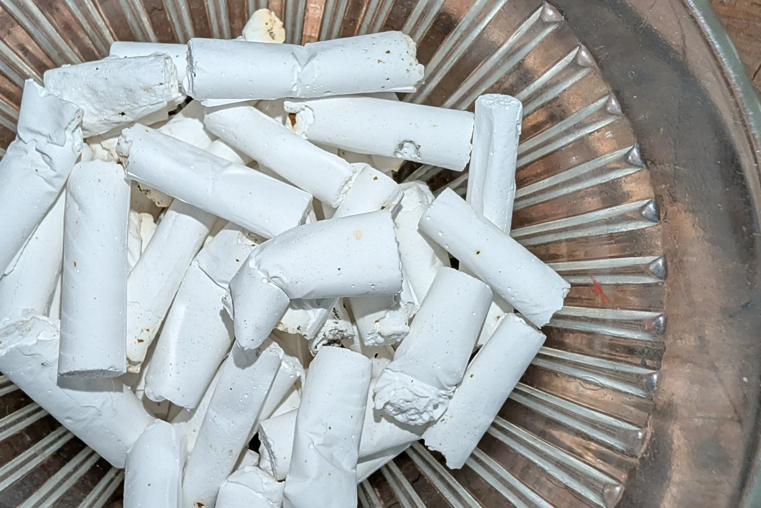 Broken white chalk pieces inside a metallic container with ridges.