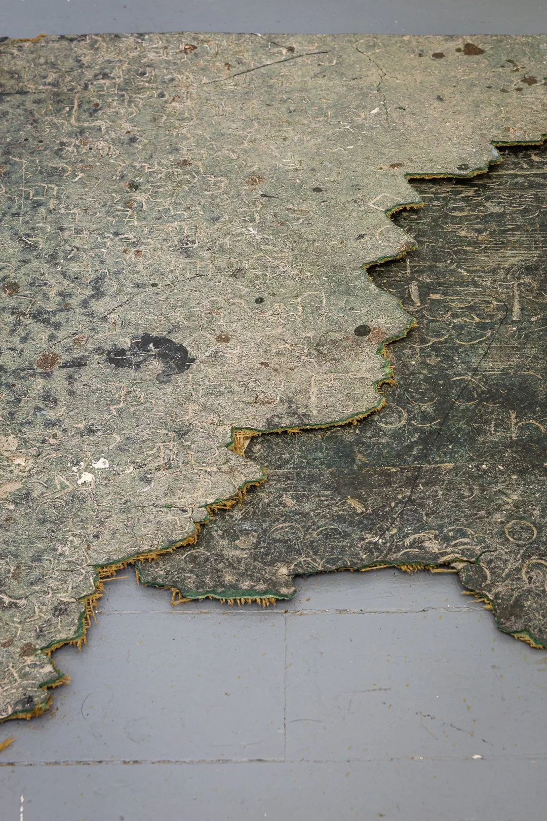 Close-up of worn, peeling paint on a surface, revealing layers beneath.