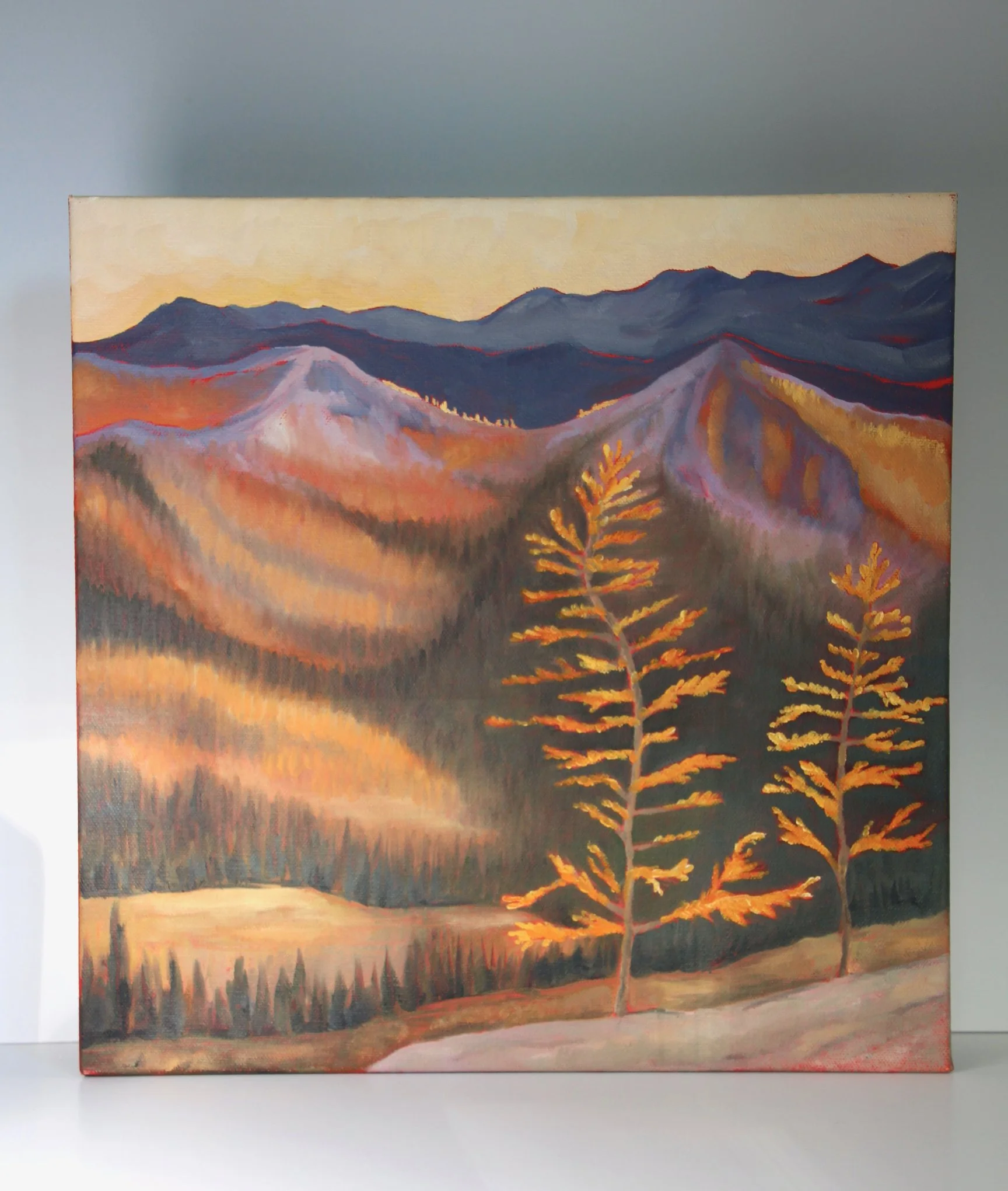 A painting of a mountain landscape at sunset with trees in the foreground.