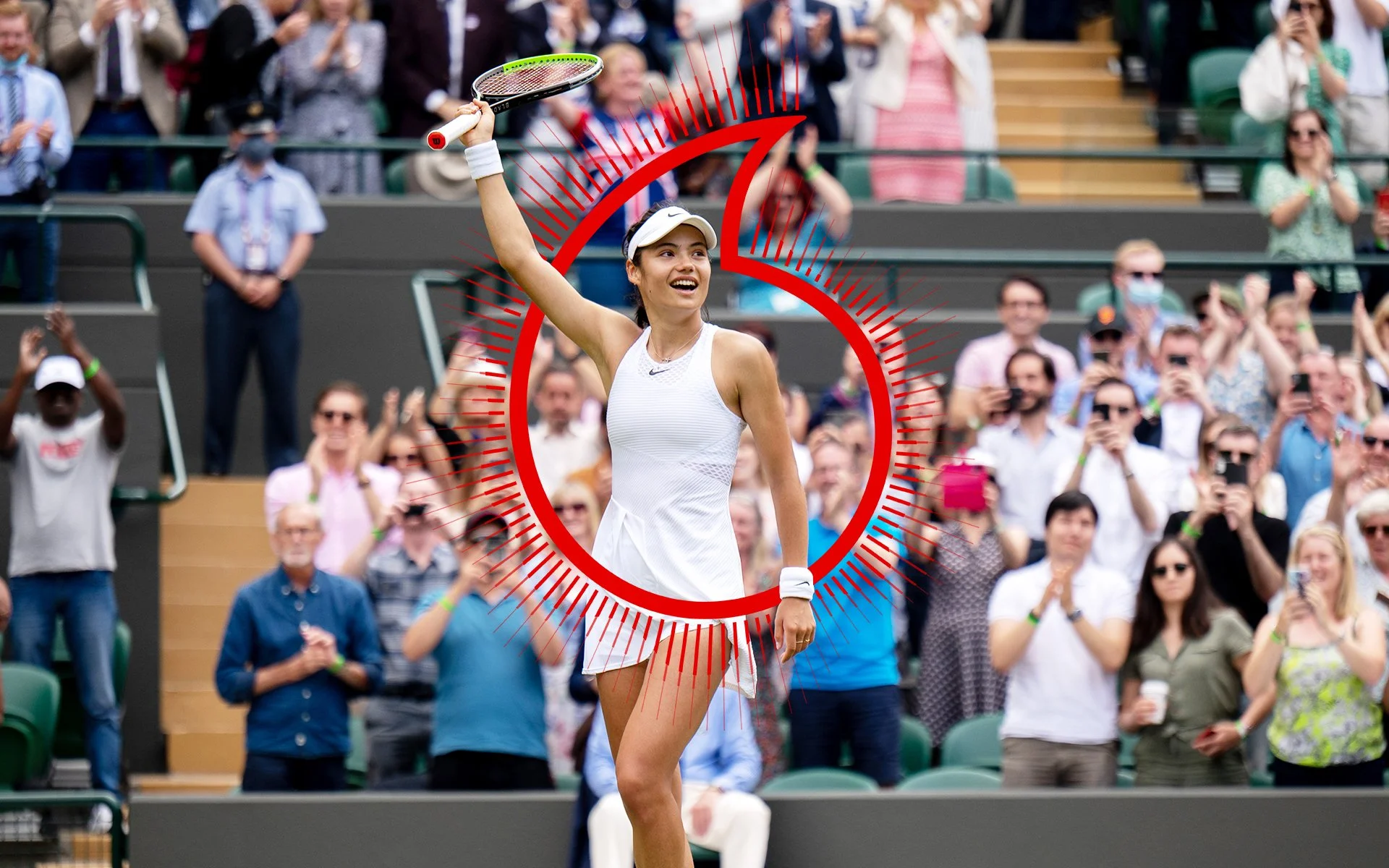 A female tennis player celebrating with a smile and holding her racket in the air, surrounded by a cheering crowd at a tennis match.