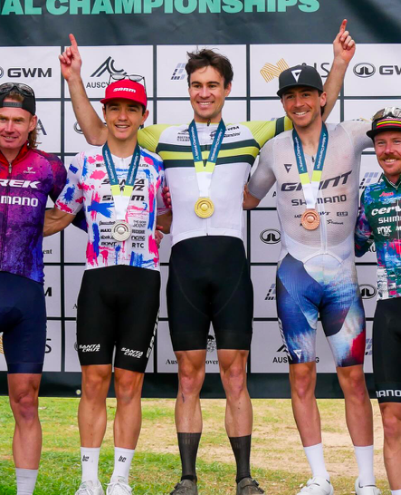 Cyclists on a winners' podium celebrating medals at a mountain biking championship.