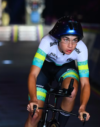 A cyclist wearing a helmet and cycling gear, riding at night in a race.