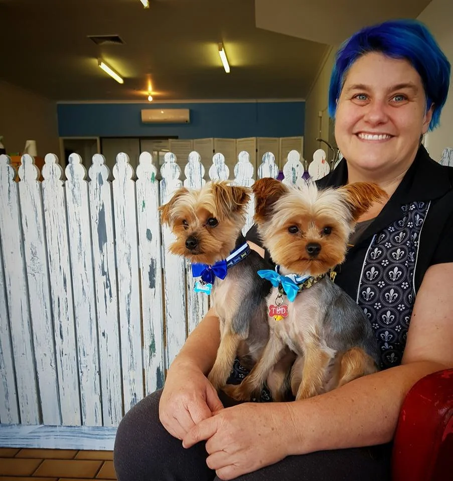 Steph Hall, founder of Yes! Canine Care, sitting with two dogs