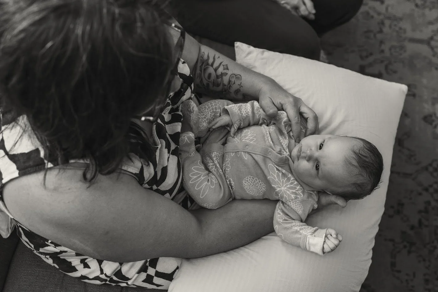 A woman holding a baby on a pillow, looking at the baby. The scene is in black and white.