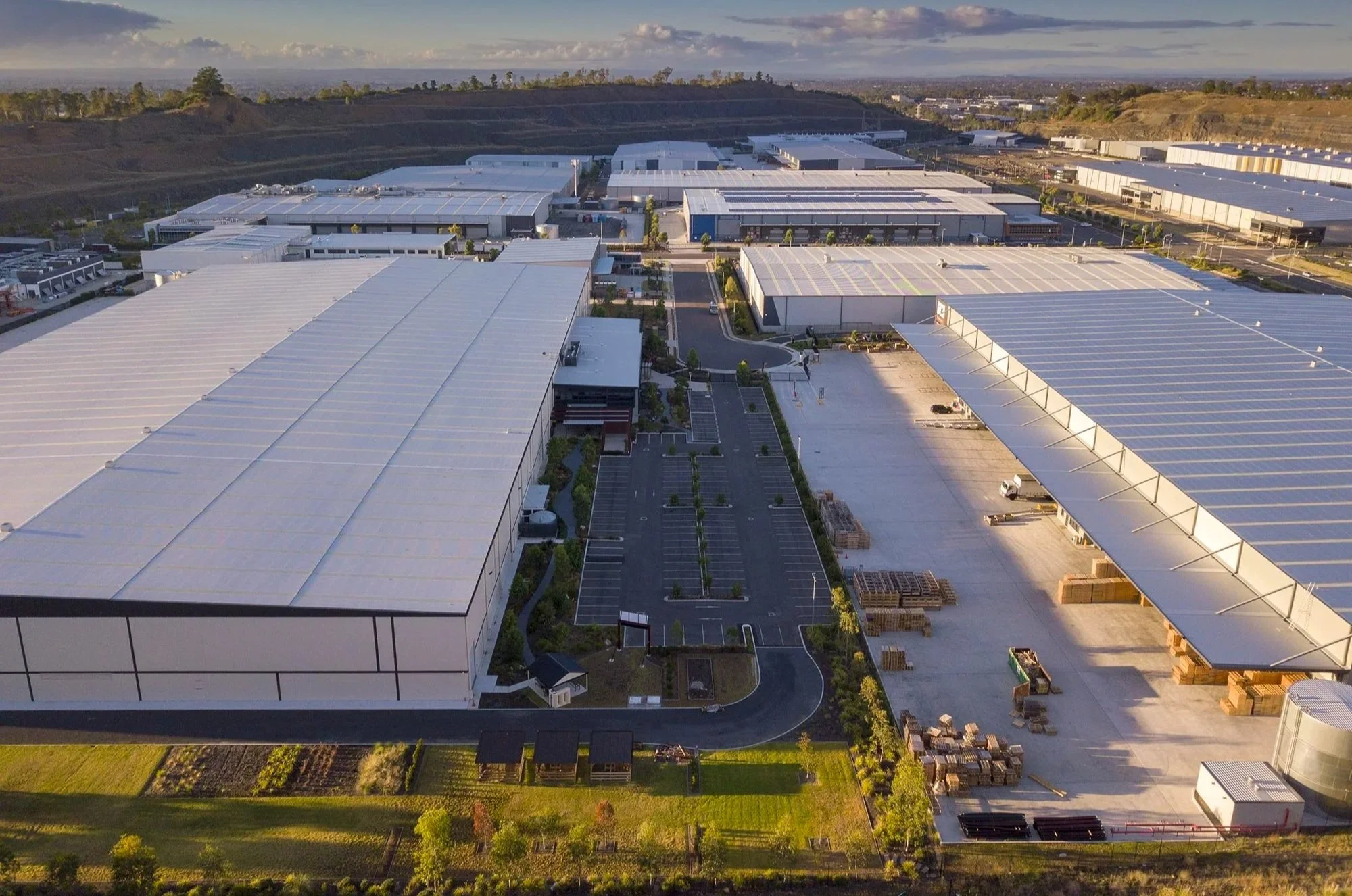 Aerial view of large industrial warehouse complex with multiple buildings, parking lots, and surrounding landscape.
