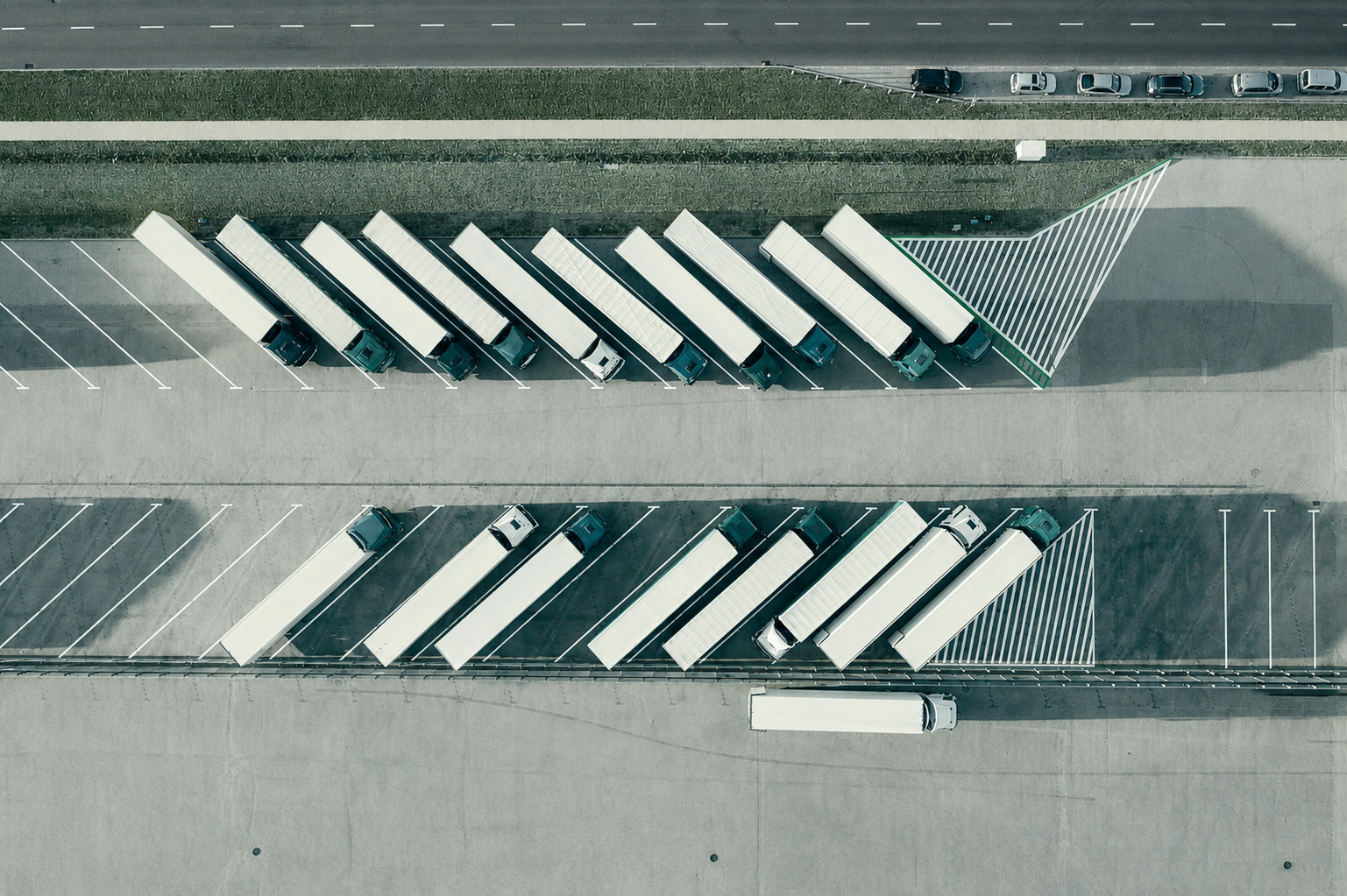 Aerial view of trucks parked in diagonal rows at a parking lot with two sections divided by an open area, with a bag of parking spaces visible at the bottom of the image.