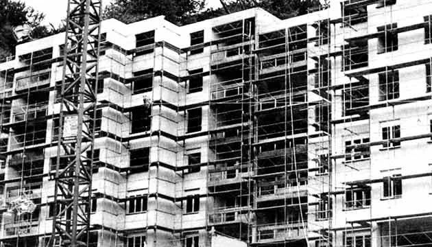 Black and white photo of a multi-story building under construction with scaffolding and a construction crane.