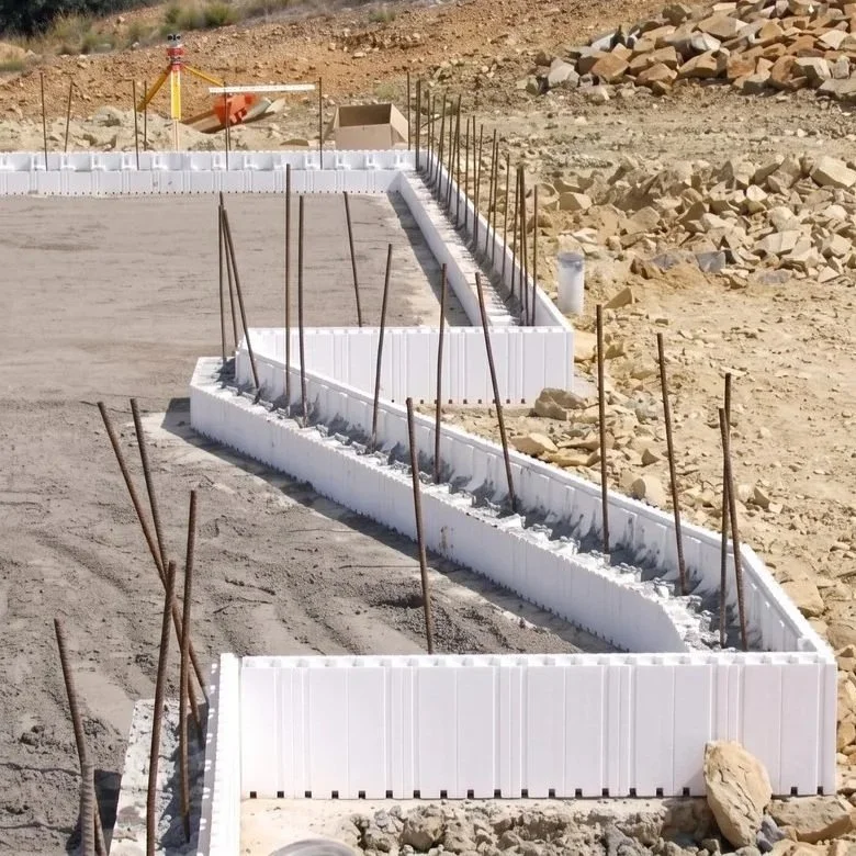 Construction site with concrete foundation and rebar stakes in a dry, rocky terrain.