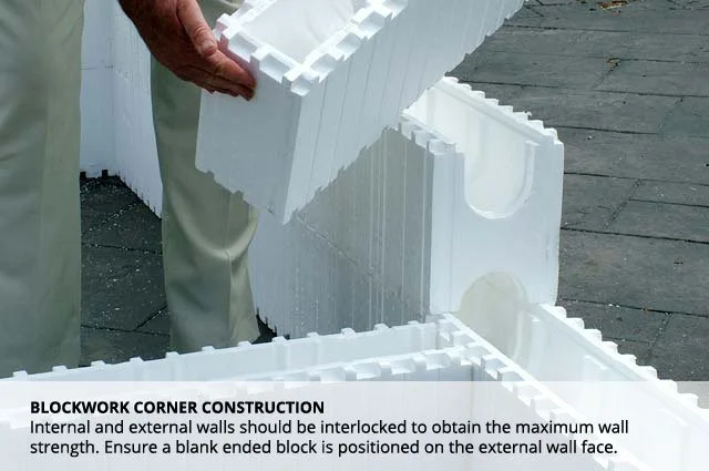 Close-up of a person's hands stacking white foam blocks for construction, with a stone or concrete surface in the background.