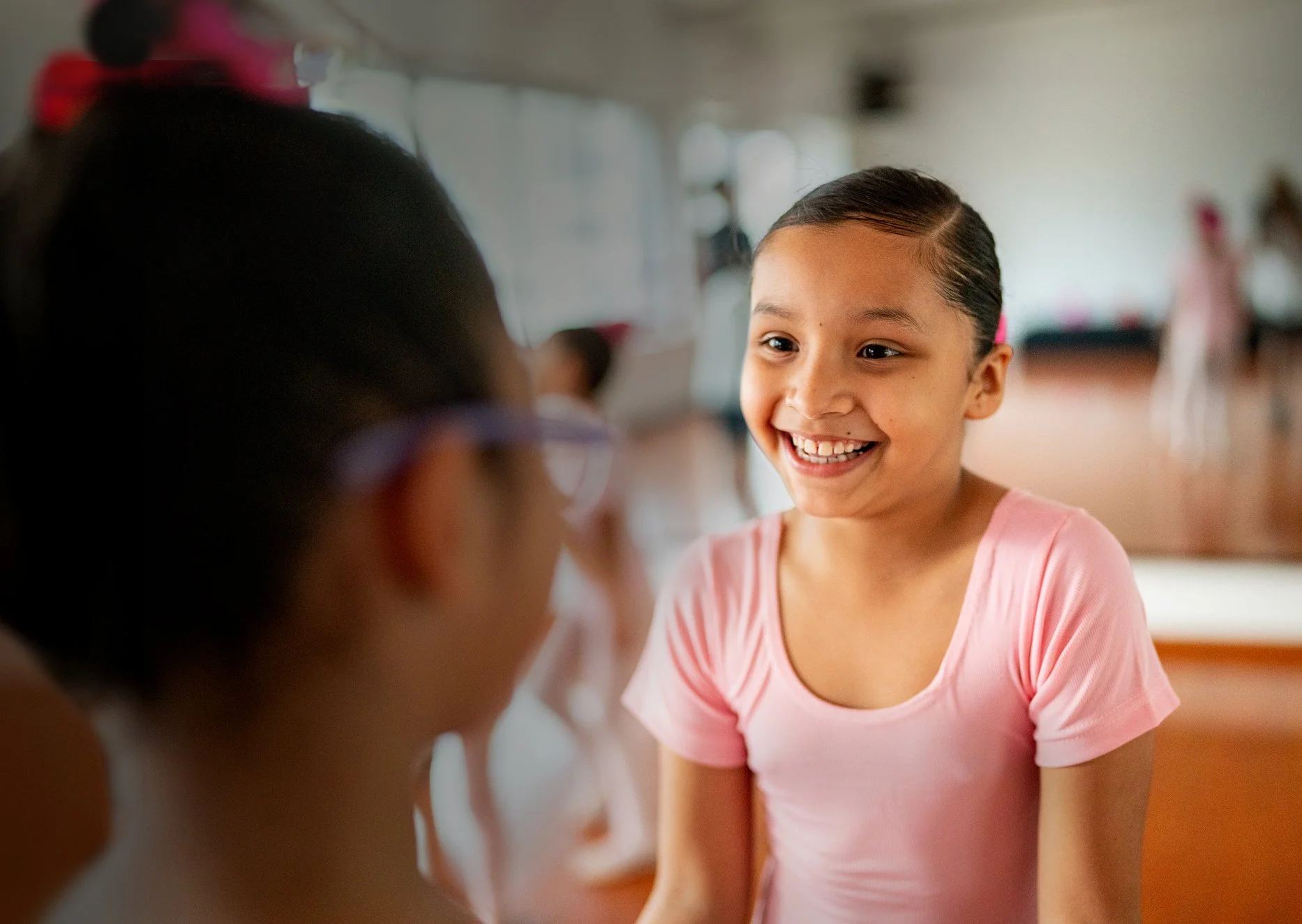 An image of two young girls in pink ballet leotards