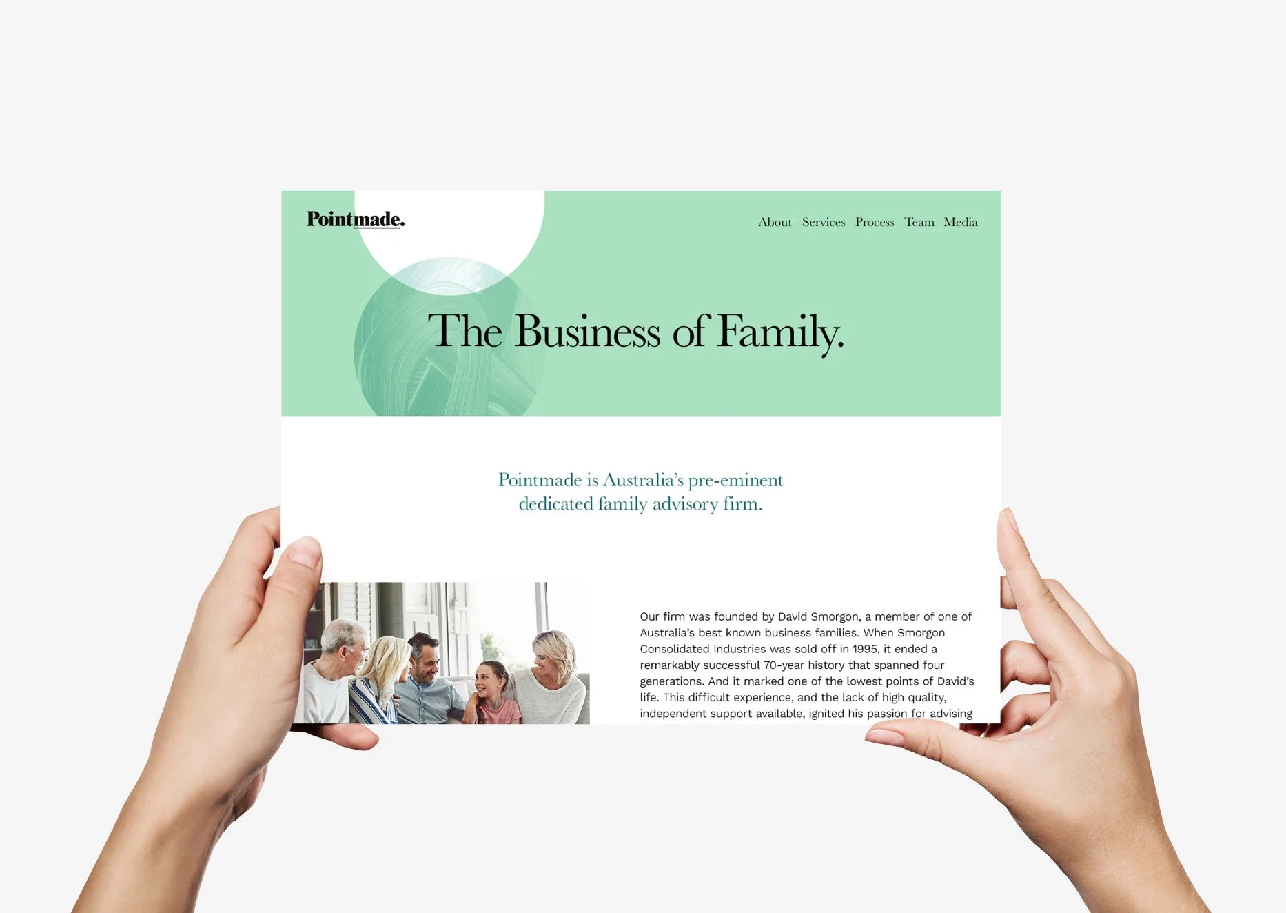 Hands holding a tablet displaying a website for a family advisory firm called Pointmade, featuring a headline 'The Business of Family' and a group of people smiling and talking in a meeting.