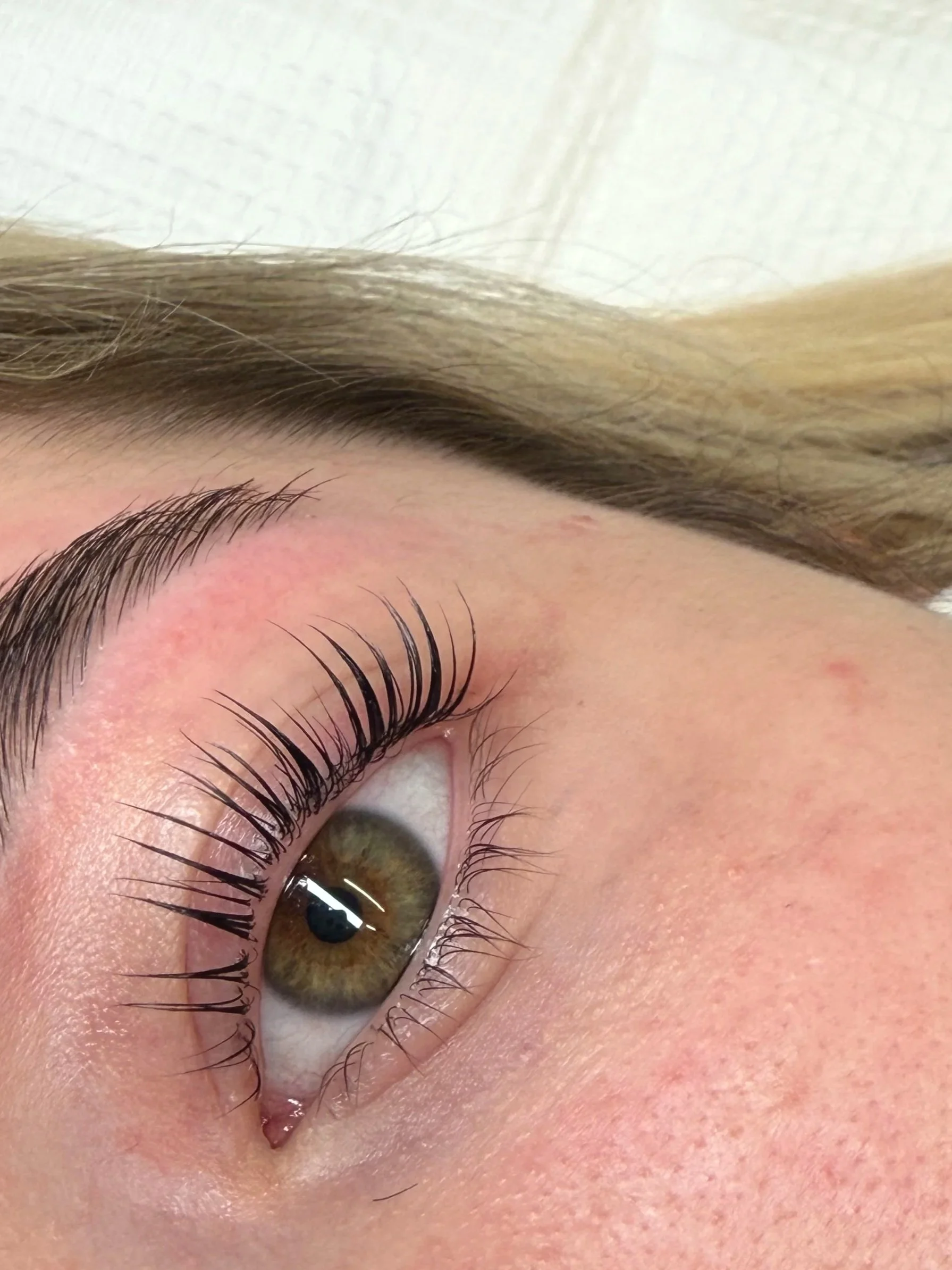 Close-up of a person's eye with long eyelashes and well-groomed eyebrows, showing skin and eye details. korean lash lift non damaging