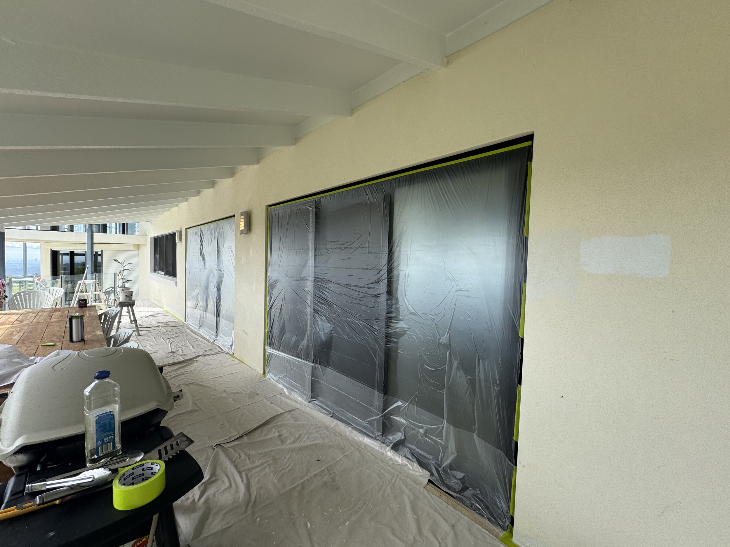 Exterior painting preparation with windows and patio areas protected before painting.