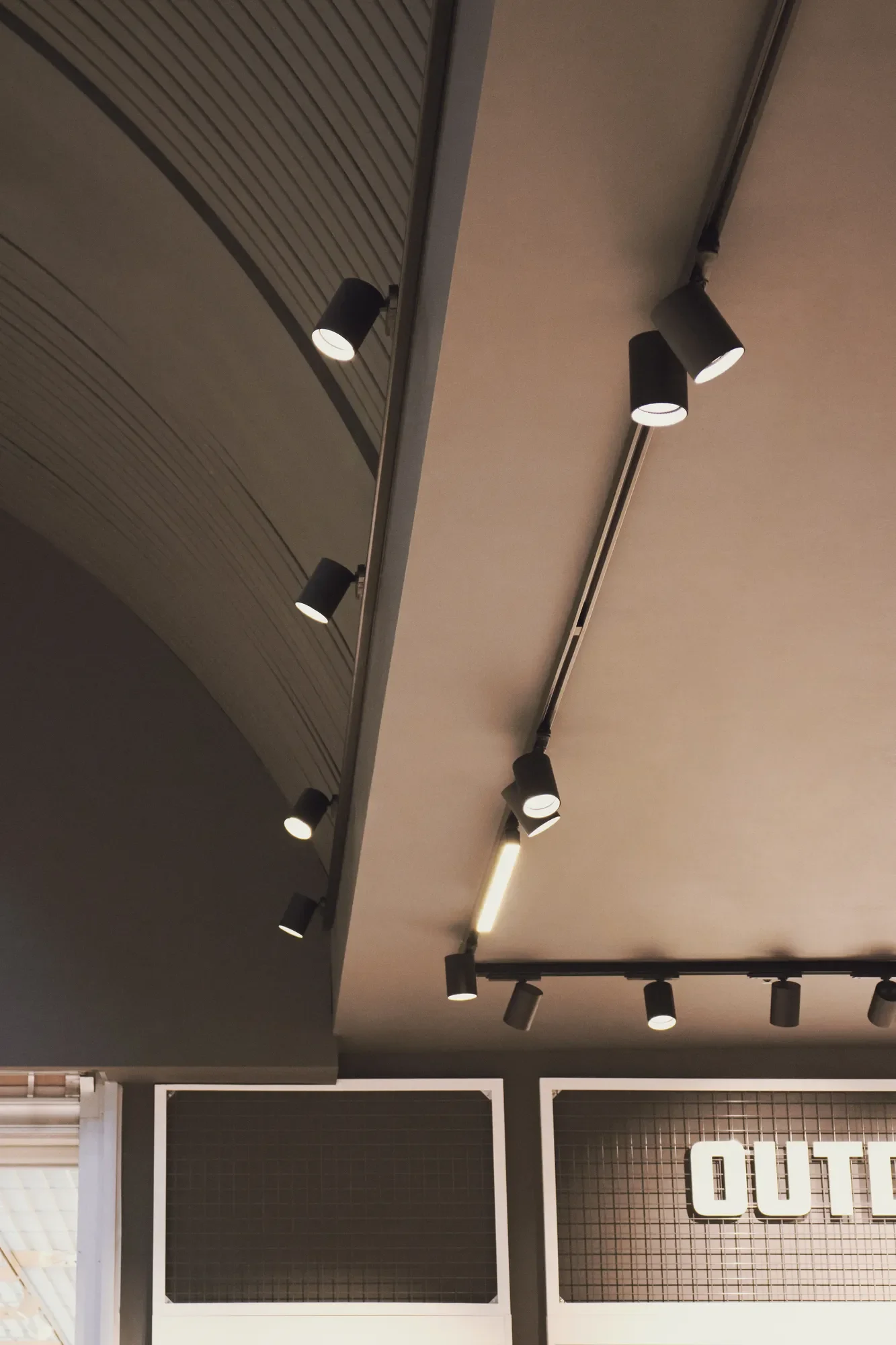 Ceiling with black track lighting fixtures illuminating the space below by LIK Lighting.