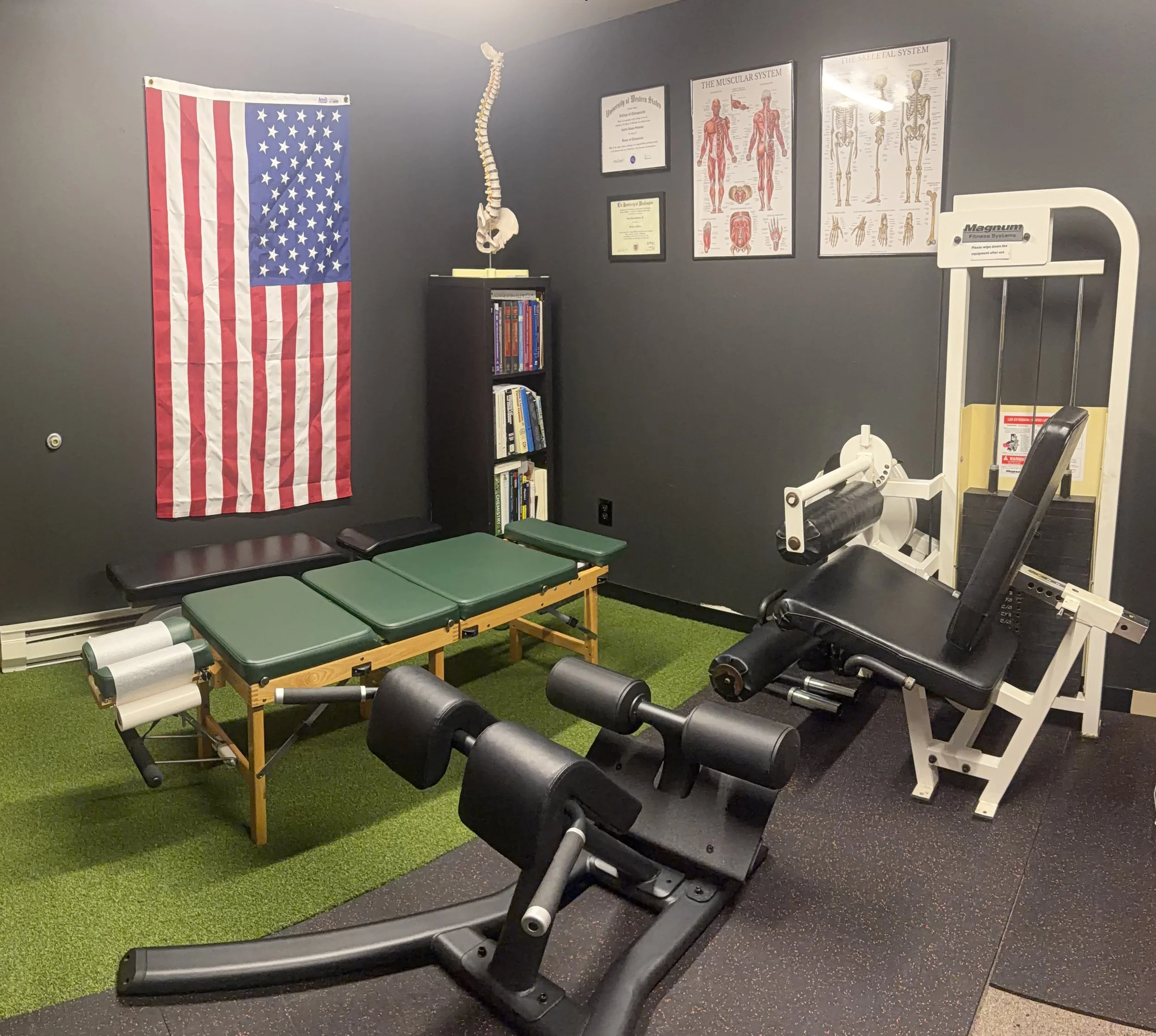 Dr. CJ Schuster DC CSCS sports chiropractic office Kirkland Eastside treatment room photo chiropractic table 45 degree hyperextensions leg curl leg extension machine green turf gym flooring