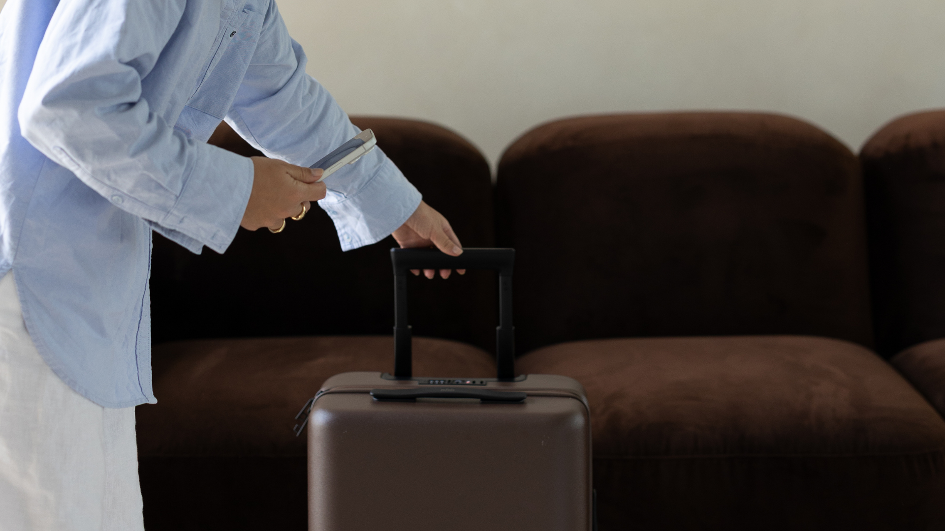 Person in a blue shirt with a travel suitcase at an airport