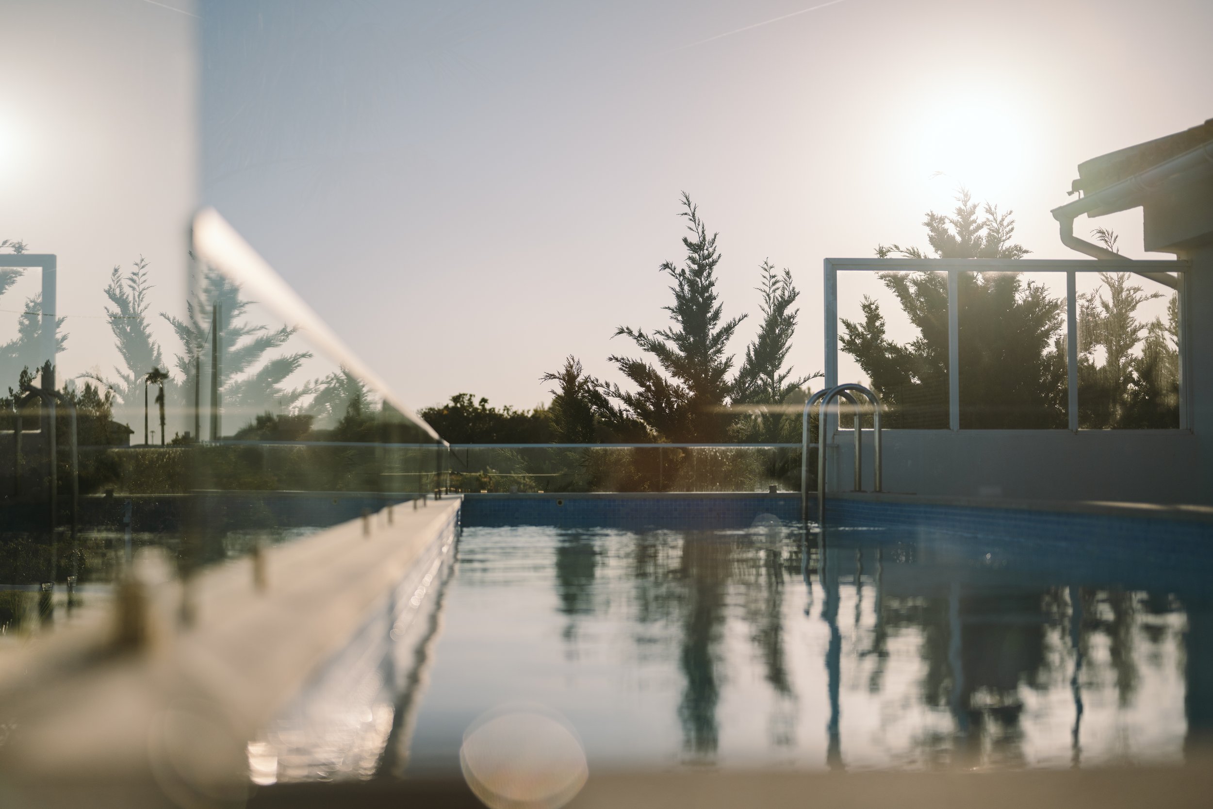 Ein Schwimmbad mit Wasser im Freien, umgeben von Bäumen und einer Sonnenenergie, die in den Himmel scheint.