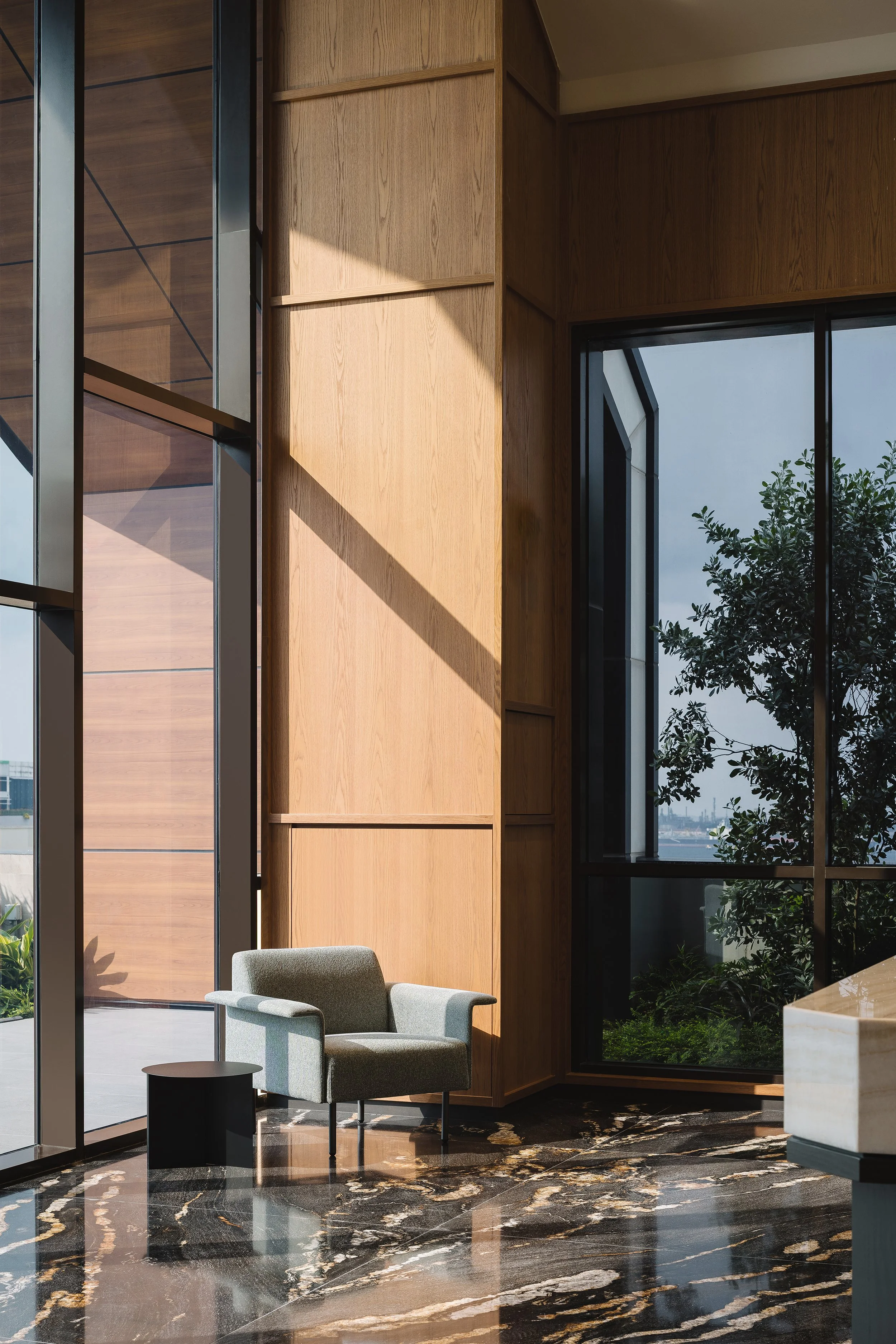Reception seating beside full-height glazing and marble floor, luxury workspace, Singapore, interior design by Rockett Studio