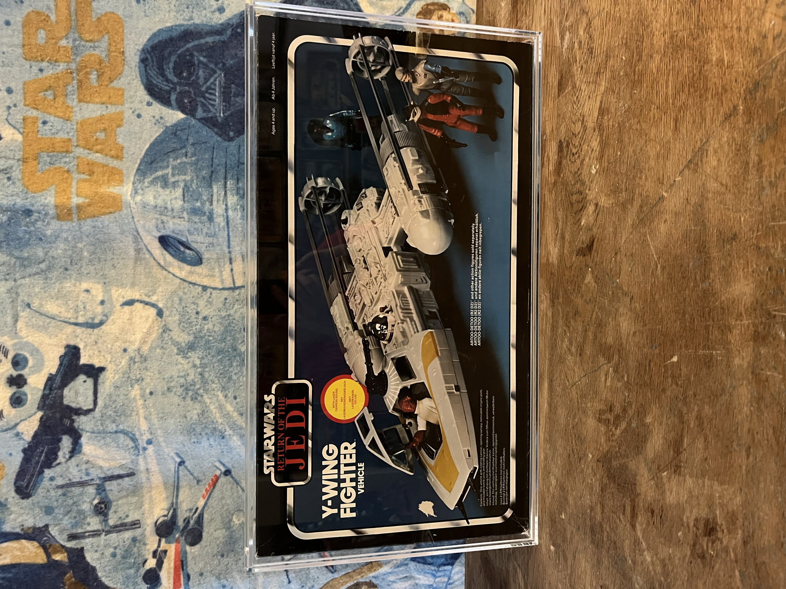 A boxed set of Star Wars Return of the Jedi vehicle models, including a speeder bike and a land speeder, displayed on a wooden surface with a Star Wars-themed cloth underneath.