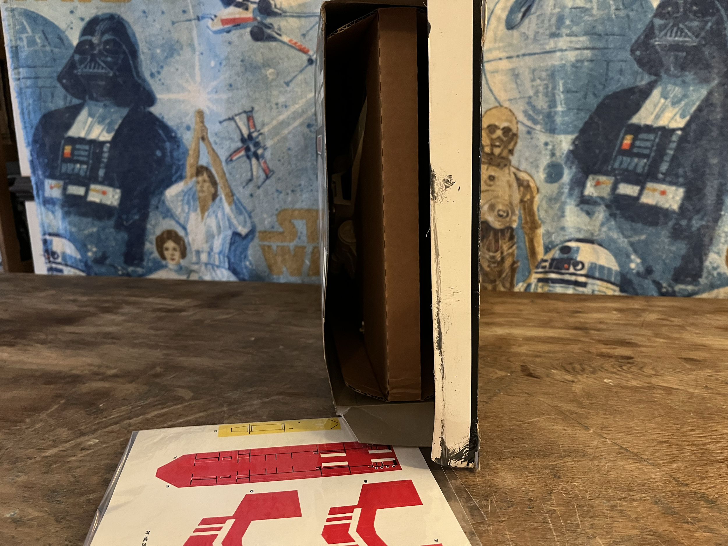 Star Wars themed puzzle box featuring Darth Vader, a TIE fighter, a stormtrooper, and R2-D2, with a partially completed puzzle laid out on a table.