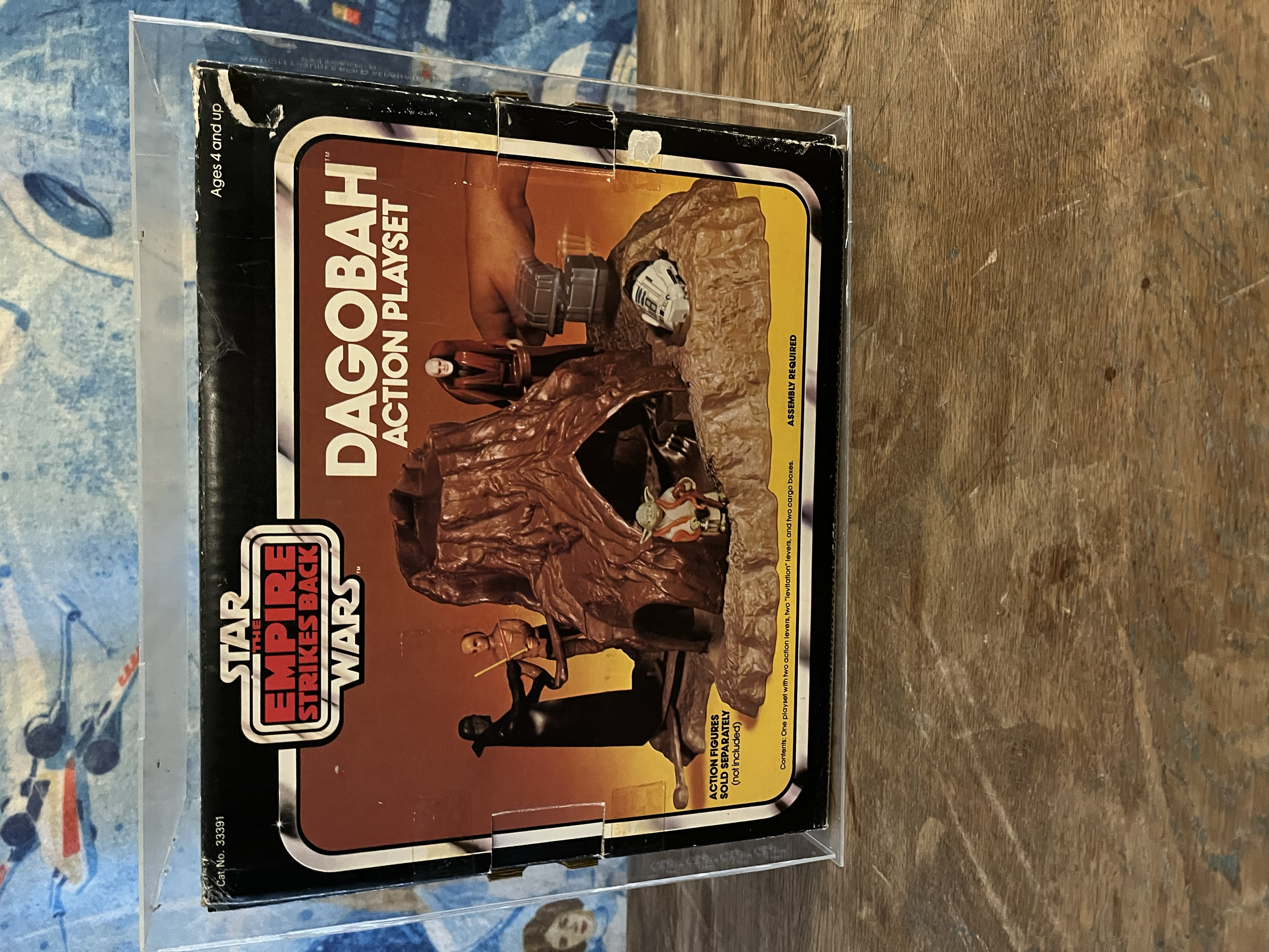 A vintage Star Wars Empire Strikes Back action figure box featuring Darth Vader and a mitrash figure, displayed in a clear plastic case on a wooden surface.
