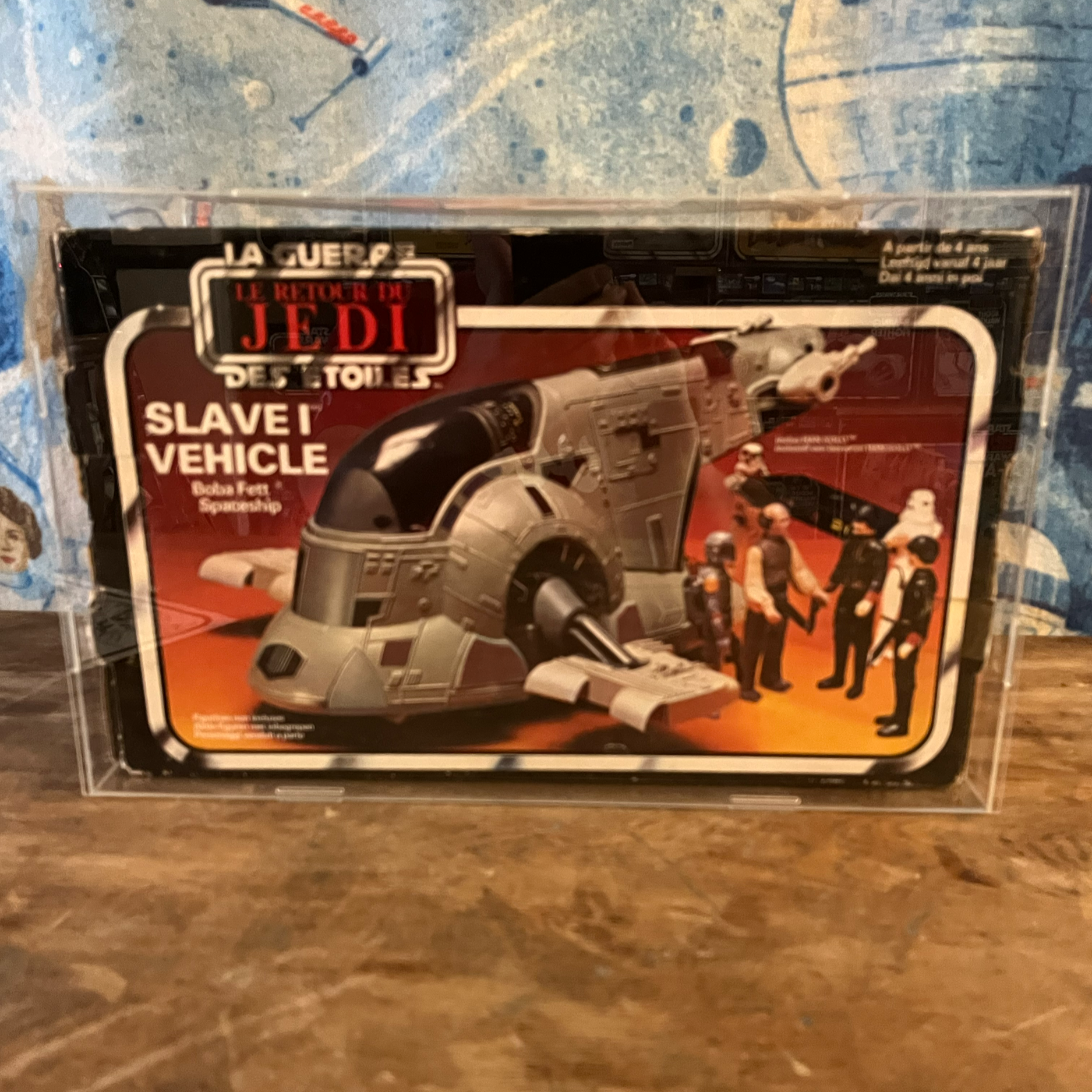 A toy Star Wars slave vehicle in its packaging, featuring action figures and a vehicle model inside a clear plastic case with Star Wars branding.
