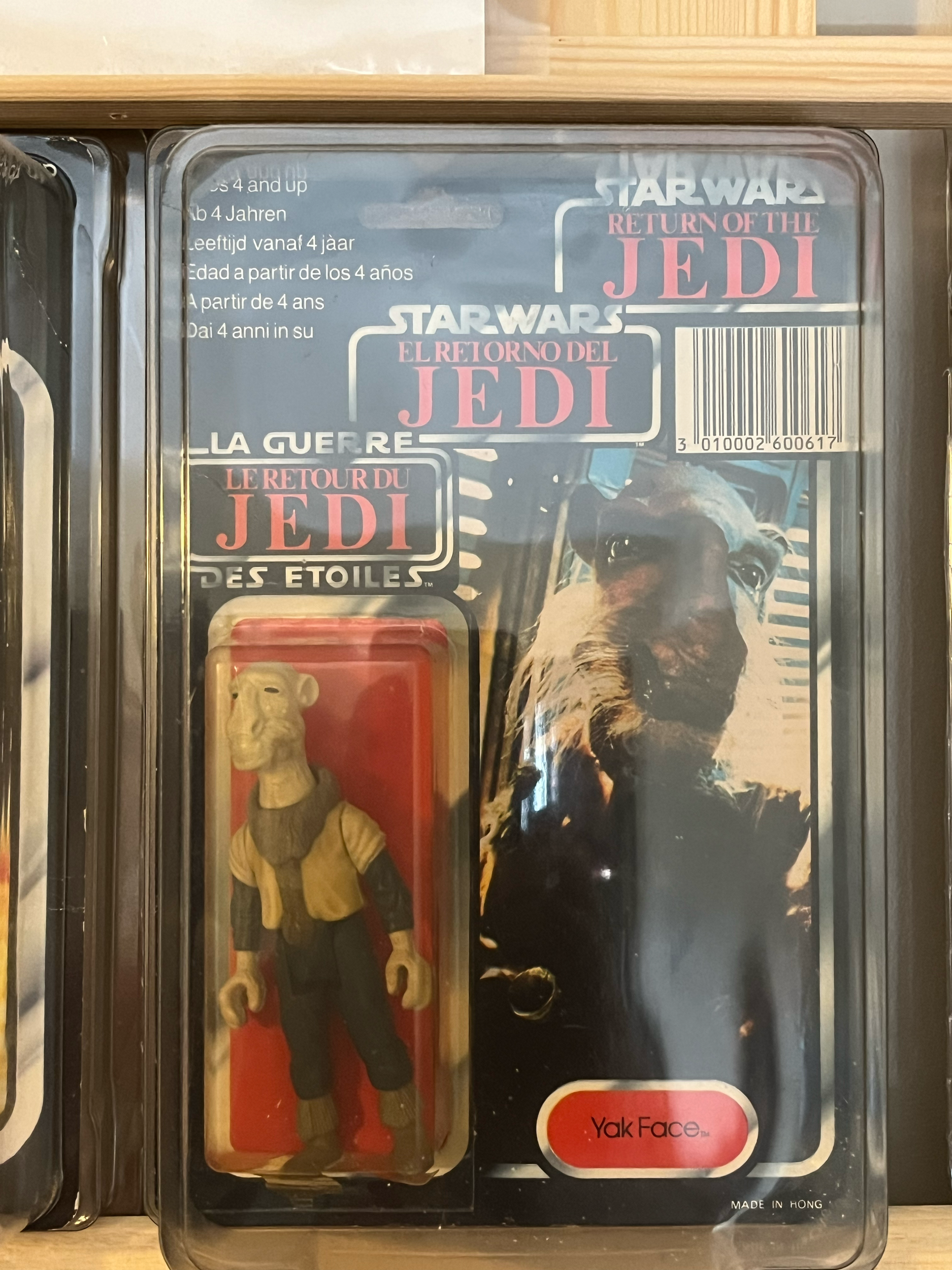 A plastic toy figure of a dog inside a sealed plastic container with a paper insert that has text and an image of a dog on it.